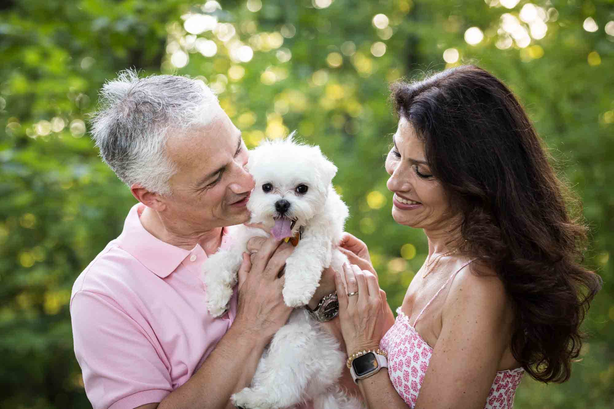 Couple focused on small, white dog during a Forest Park family photo shoot