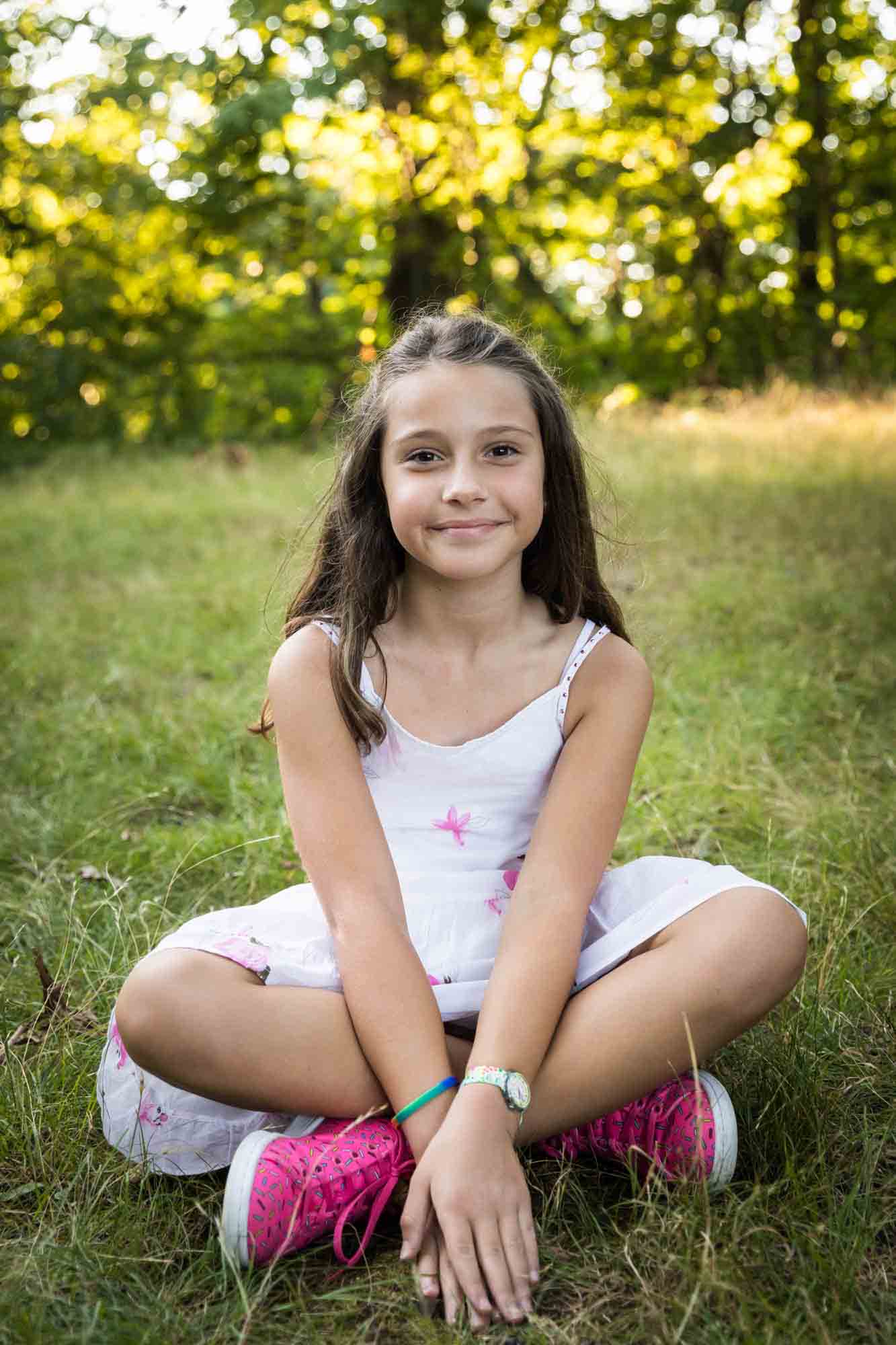 Young girl sitting on ground during a Forest Park family photo shoot
