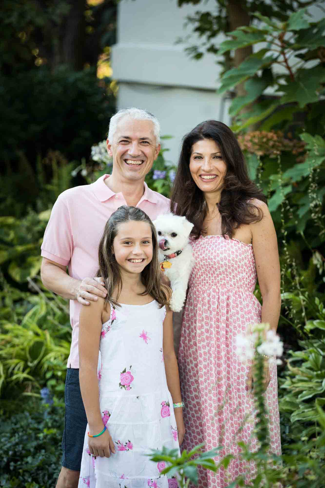 Family with young girl and white dog in front of garden during a Forest Park family photo shoot