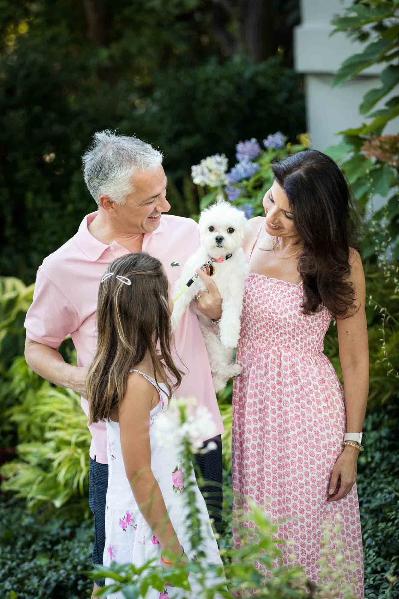 Parents and young girl looking at white dog in man's arms during a Forest Park family photo shoot