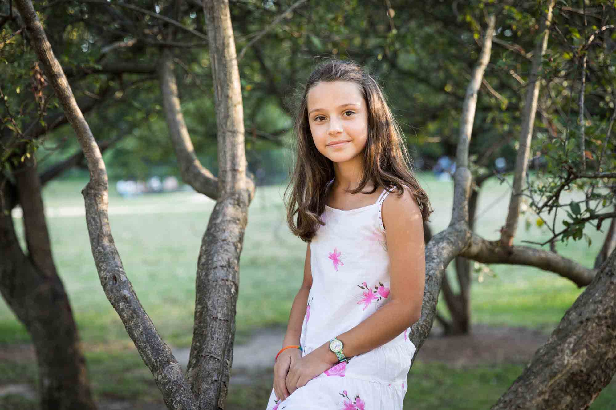 Young girl sitting in a tree during a Forest Park family photo shoot
