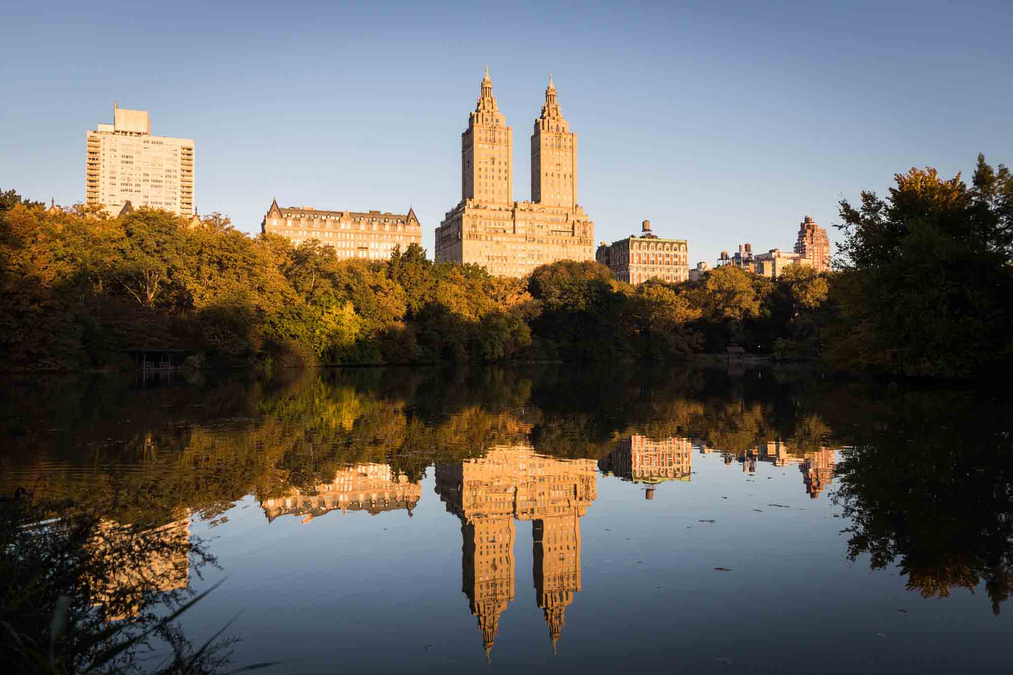 View over lake in Central Park with buildings in background at sunrise