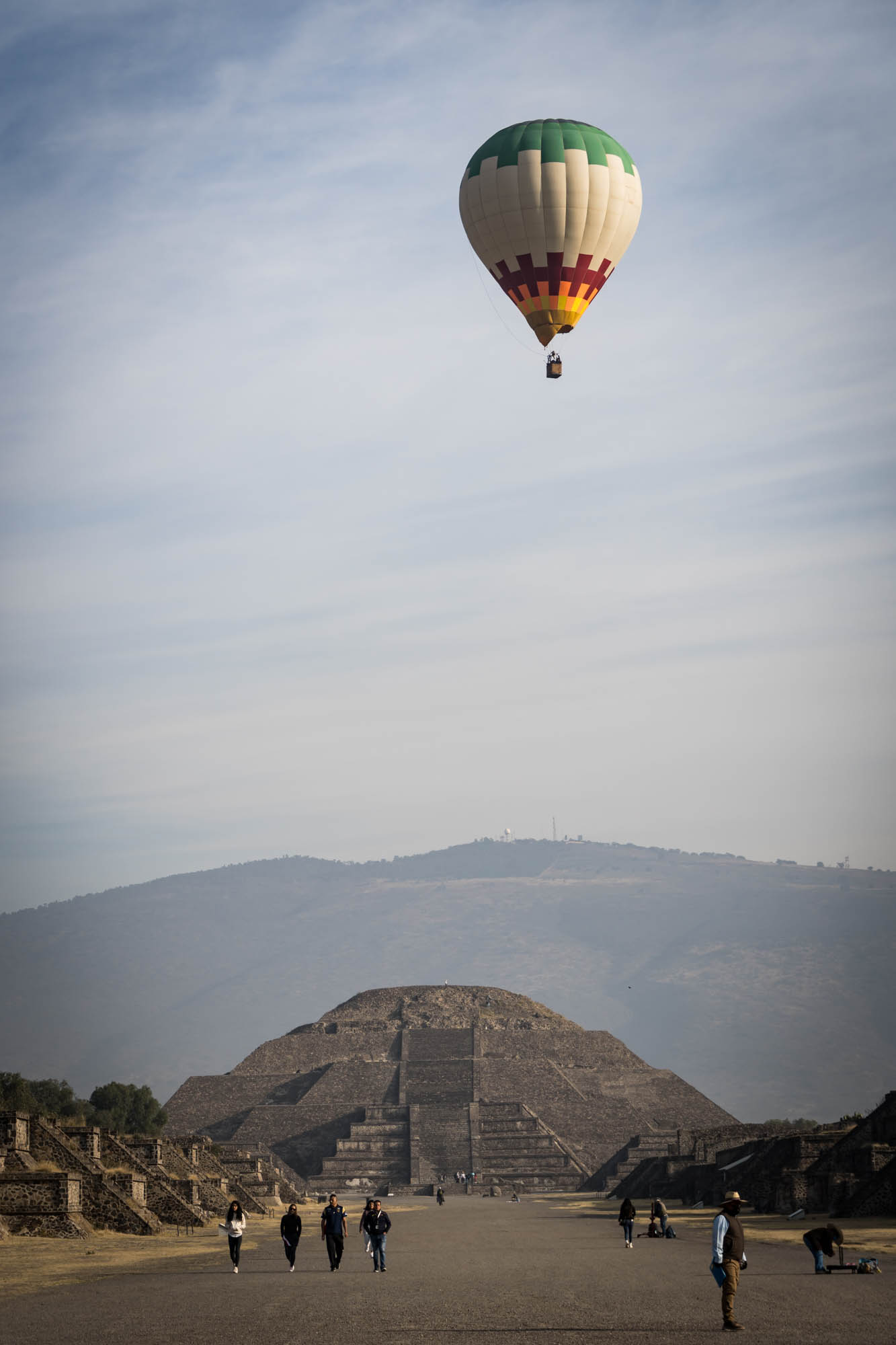 A colorful hot air balloon floats above a pyramid at Teotihuacan