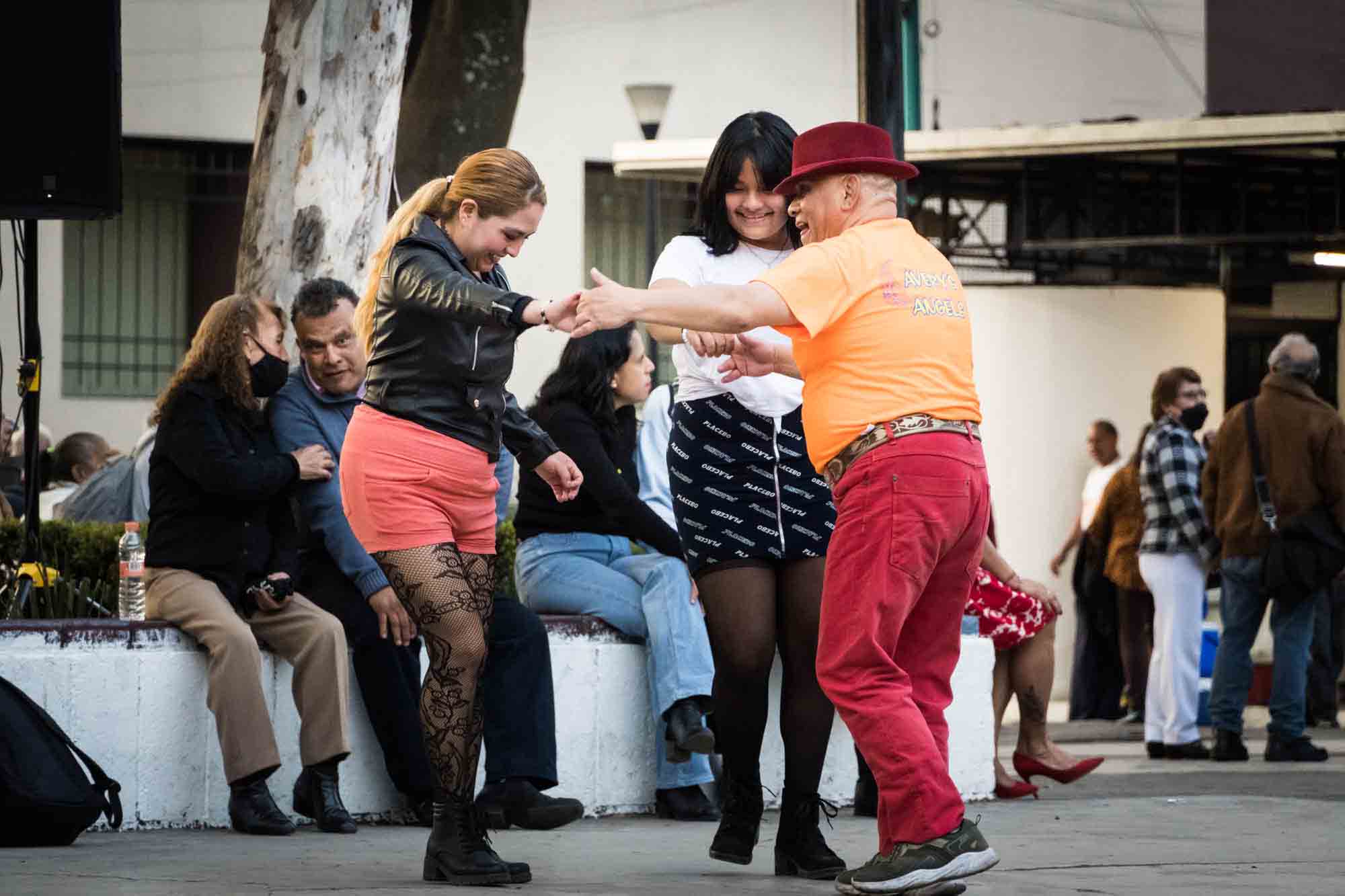 A man and two women dance on the sidewalk in Mexico City