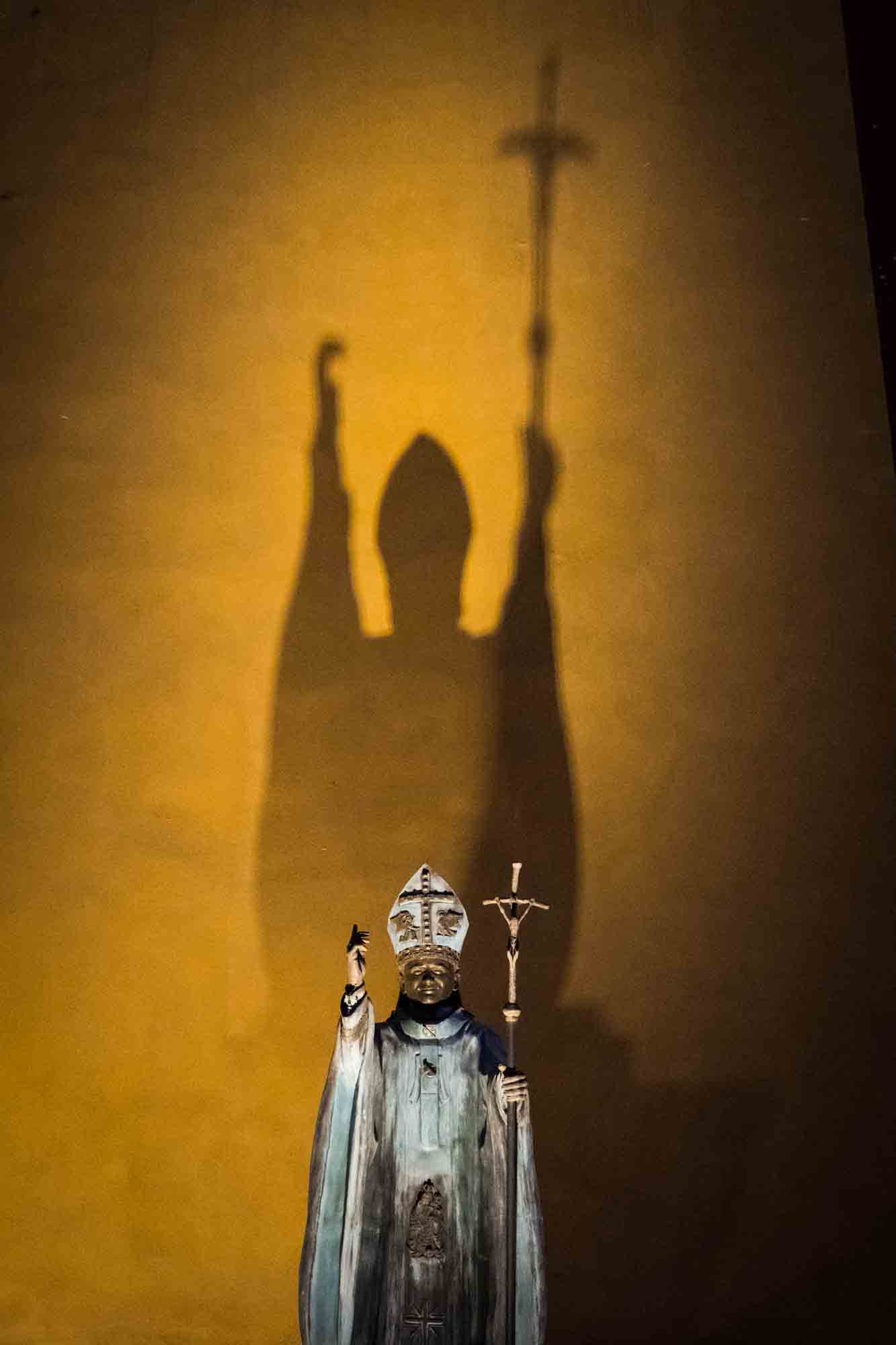 Shadows cast against a statue of a pope in Guanajuato