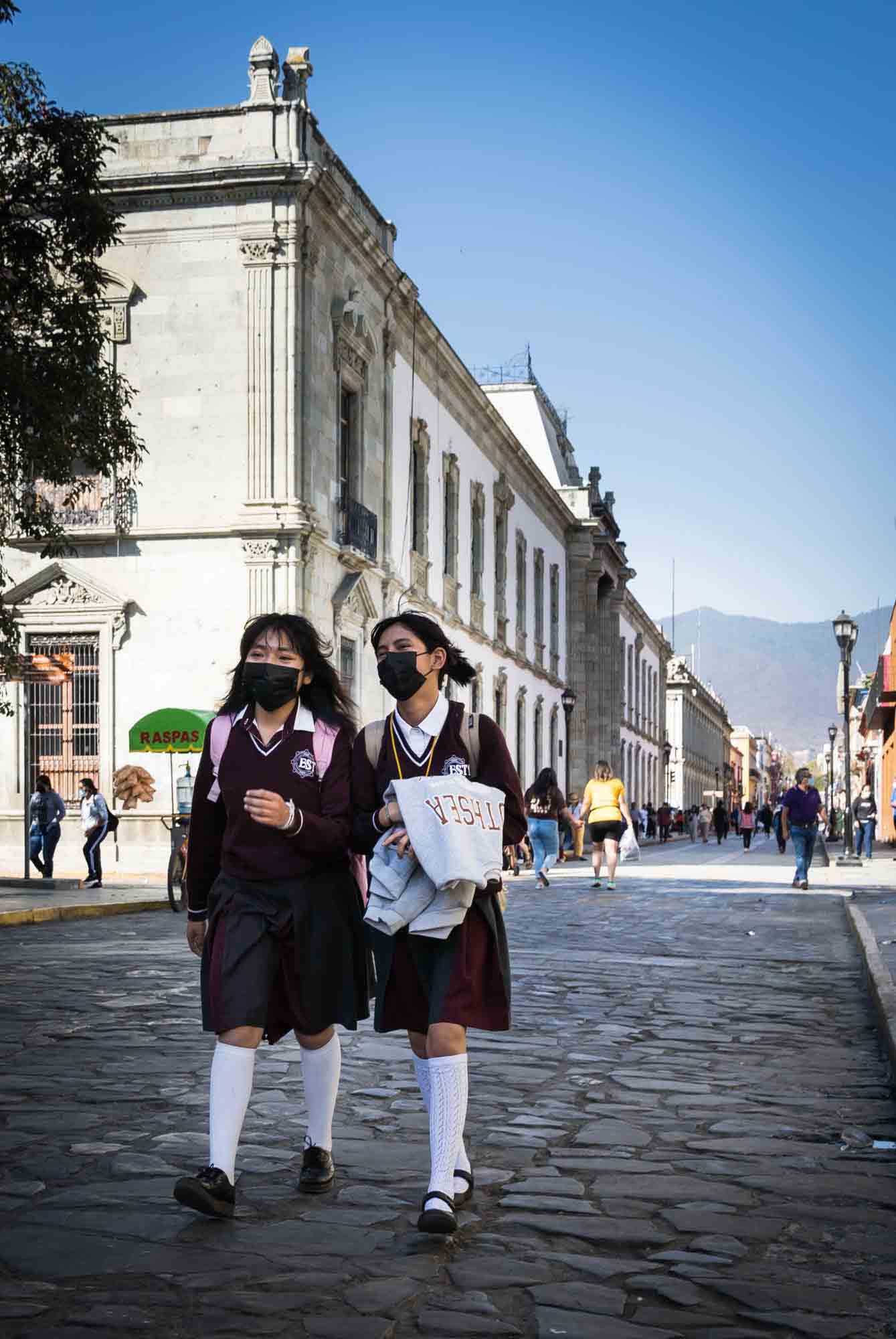Two school girls walk down the Anador Turistico in Oaxaca