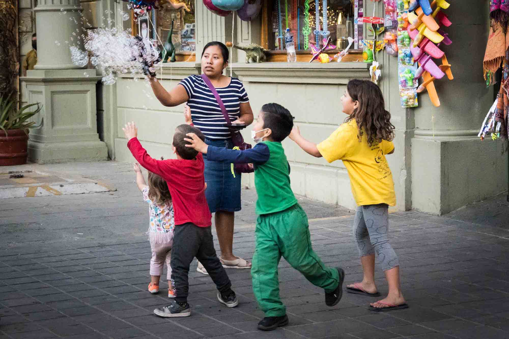 Little kids chasing after a woman blowing bubbles in Oaxaca