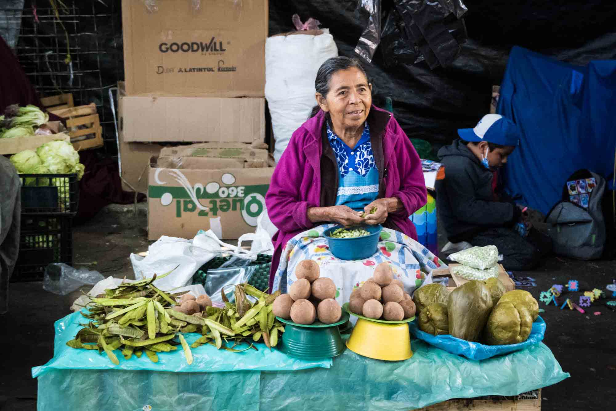 A woman sells produce on a table in the Oaxaca market