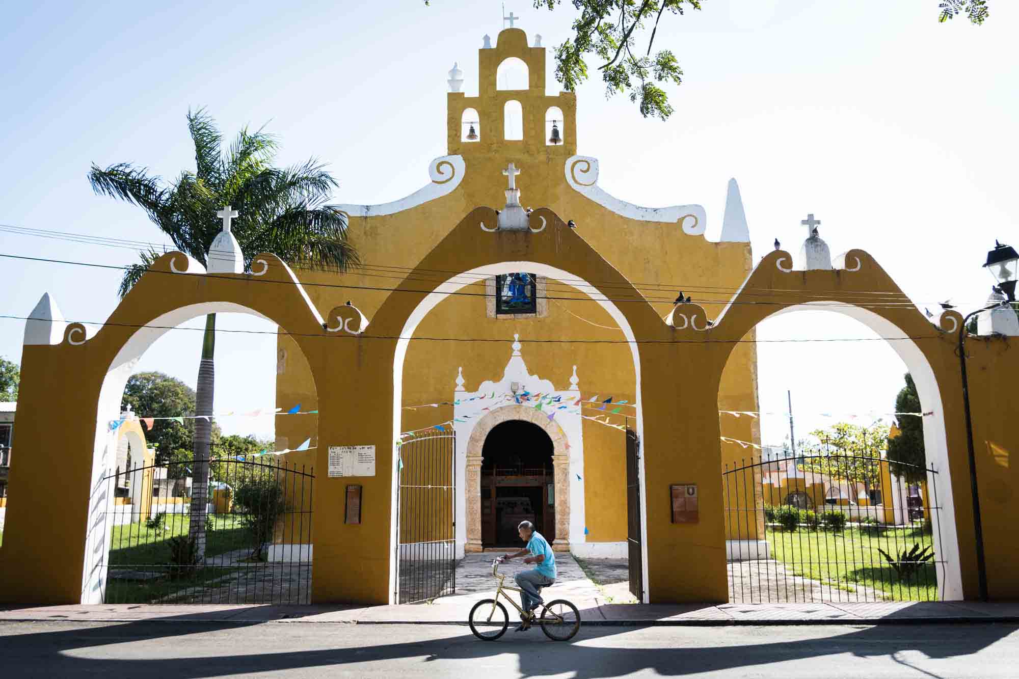 Man riding a bicycle past a yellow church in Valladolid