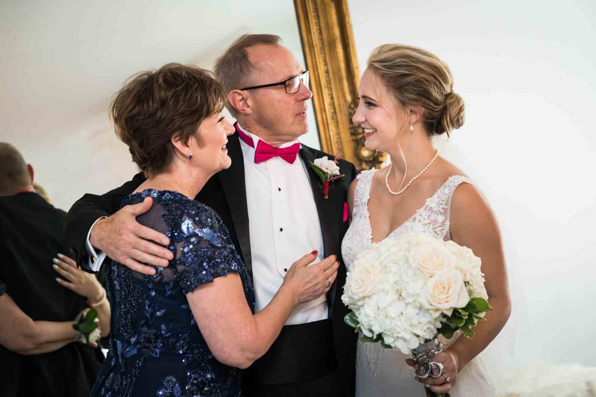 Bride embracing parents in front of mirror at a Briarcliff Manor wedding