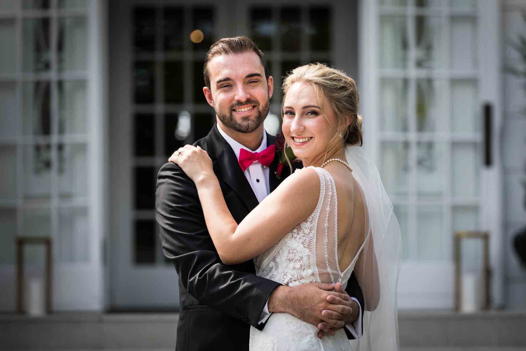 Bride and groom hugging in front of French doors at a Briarcliff Manor wedding