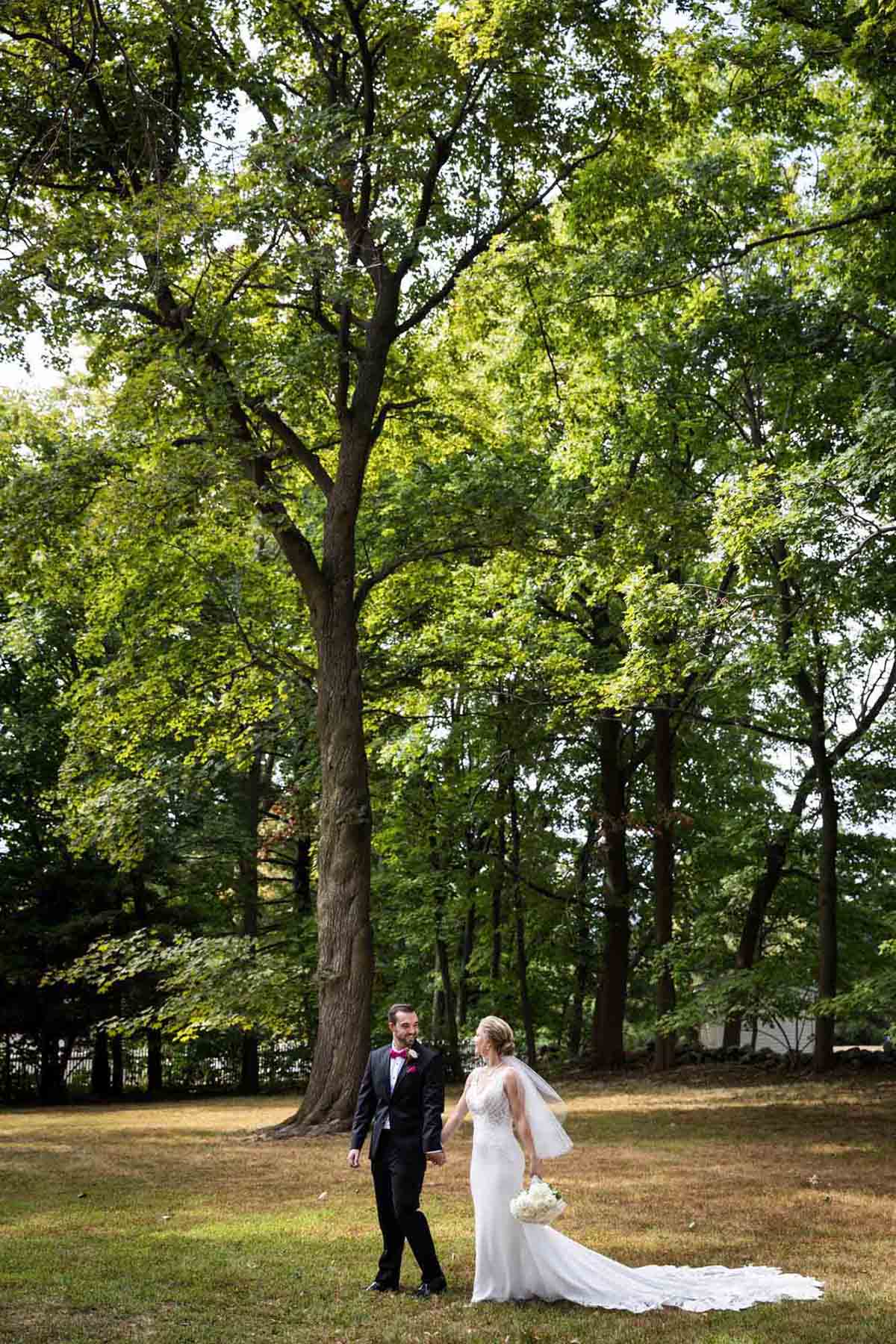 Bride and groom walking in forest in front of trees at a Briarcliff Manor wedding