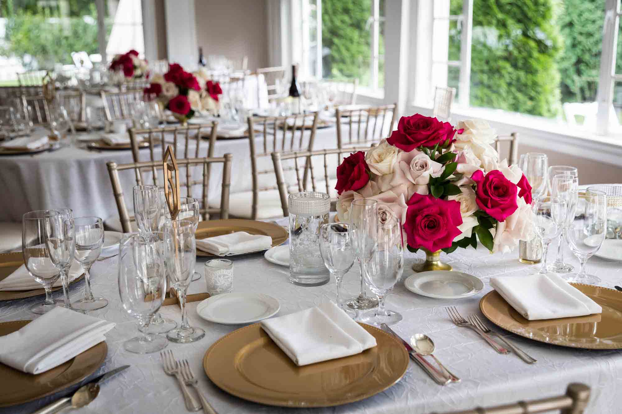 Tables set with gold chargers and rose floral centerpieces at a Briarcliff Manor wedding