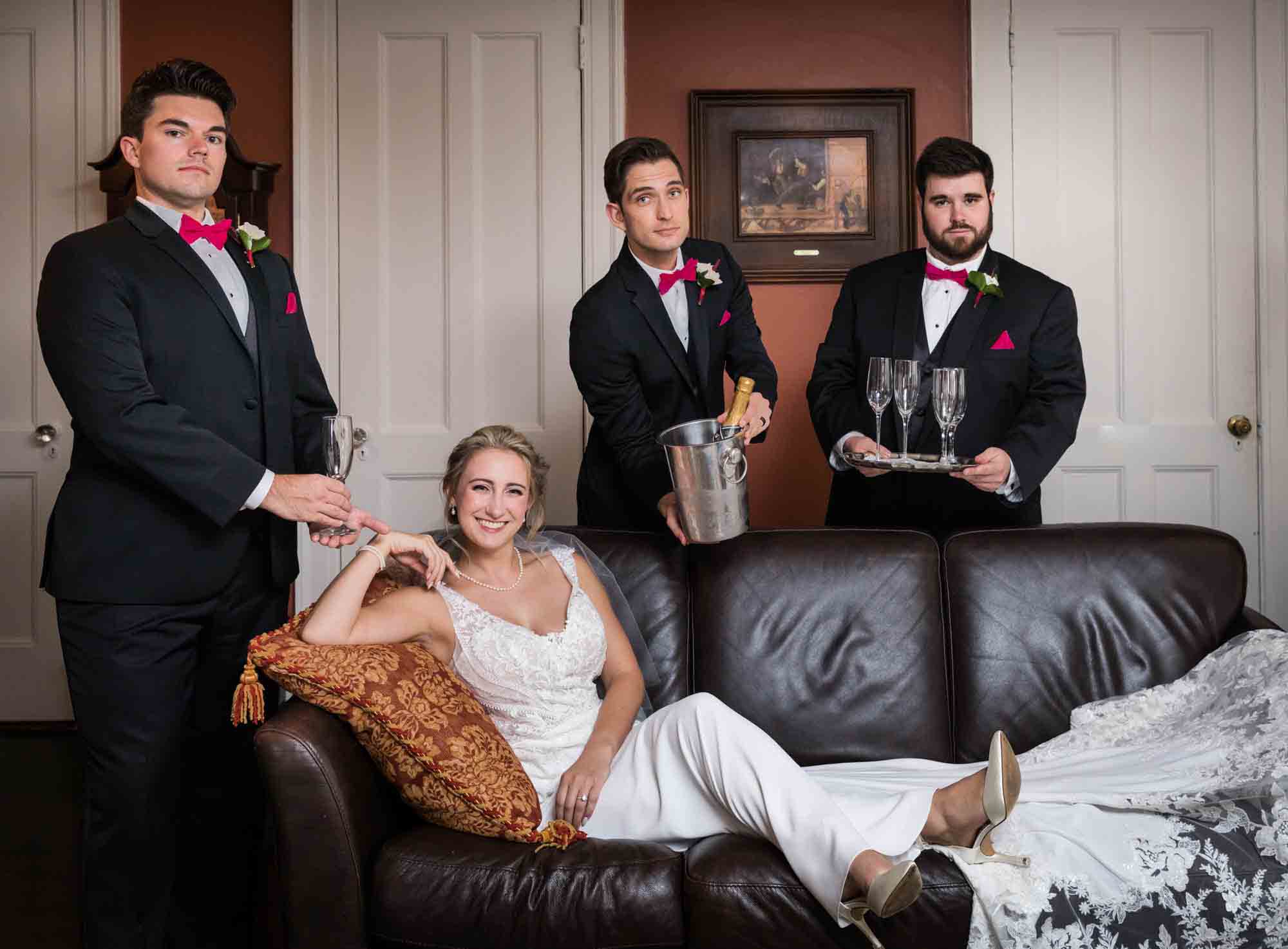 Bride lying on leather couch surrounded by three groomsmen at a Briarcliff Manor wedding
