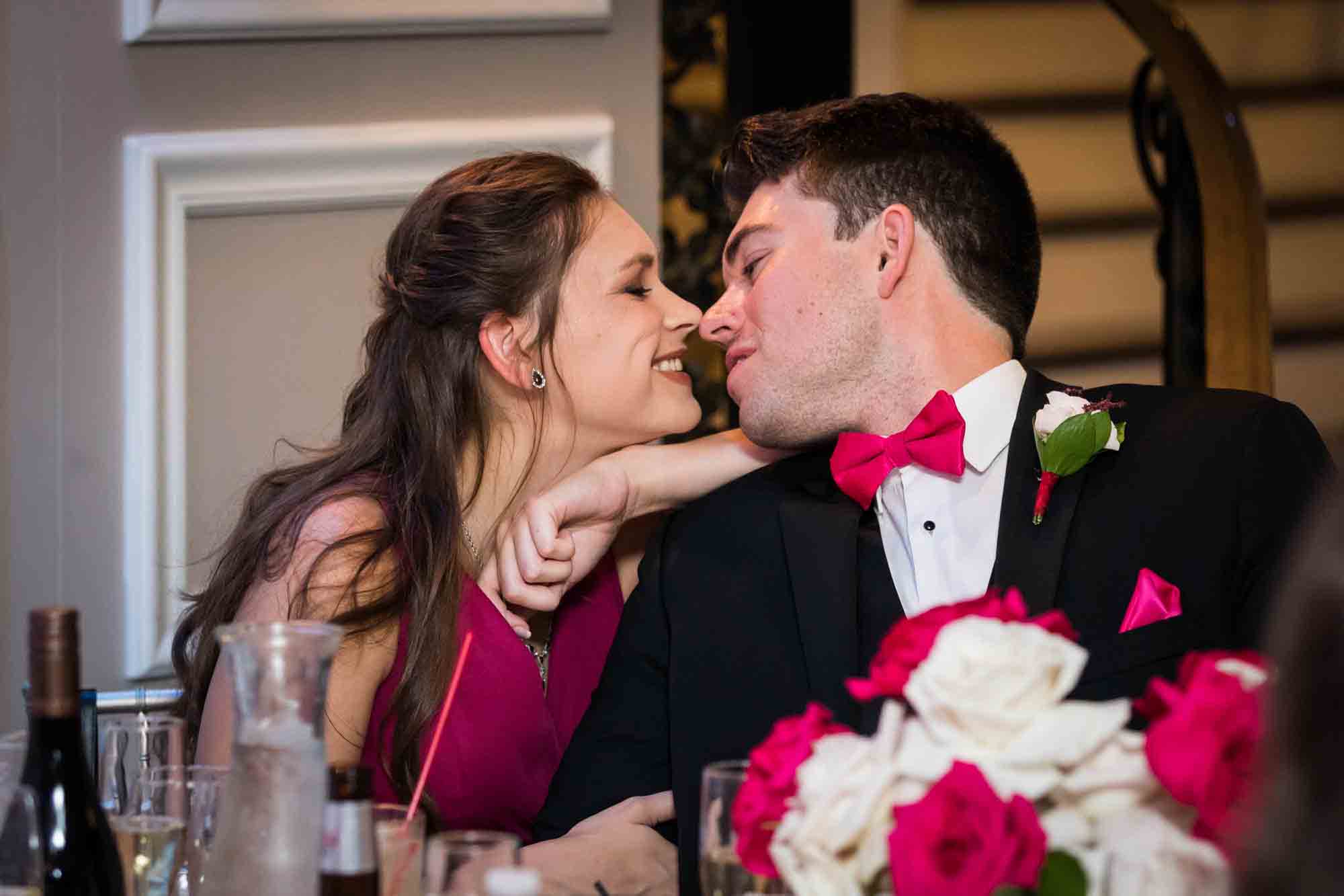 Guest wearing pink dress kissing man wearing pink bow tie at a Briarcliff Manor wedding