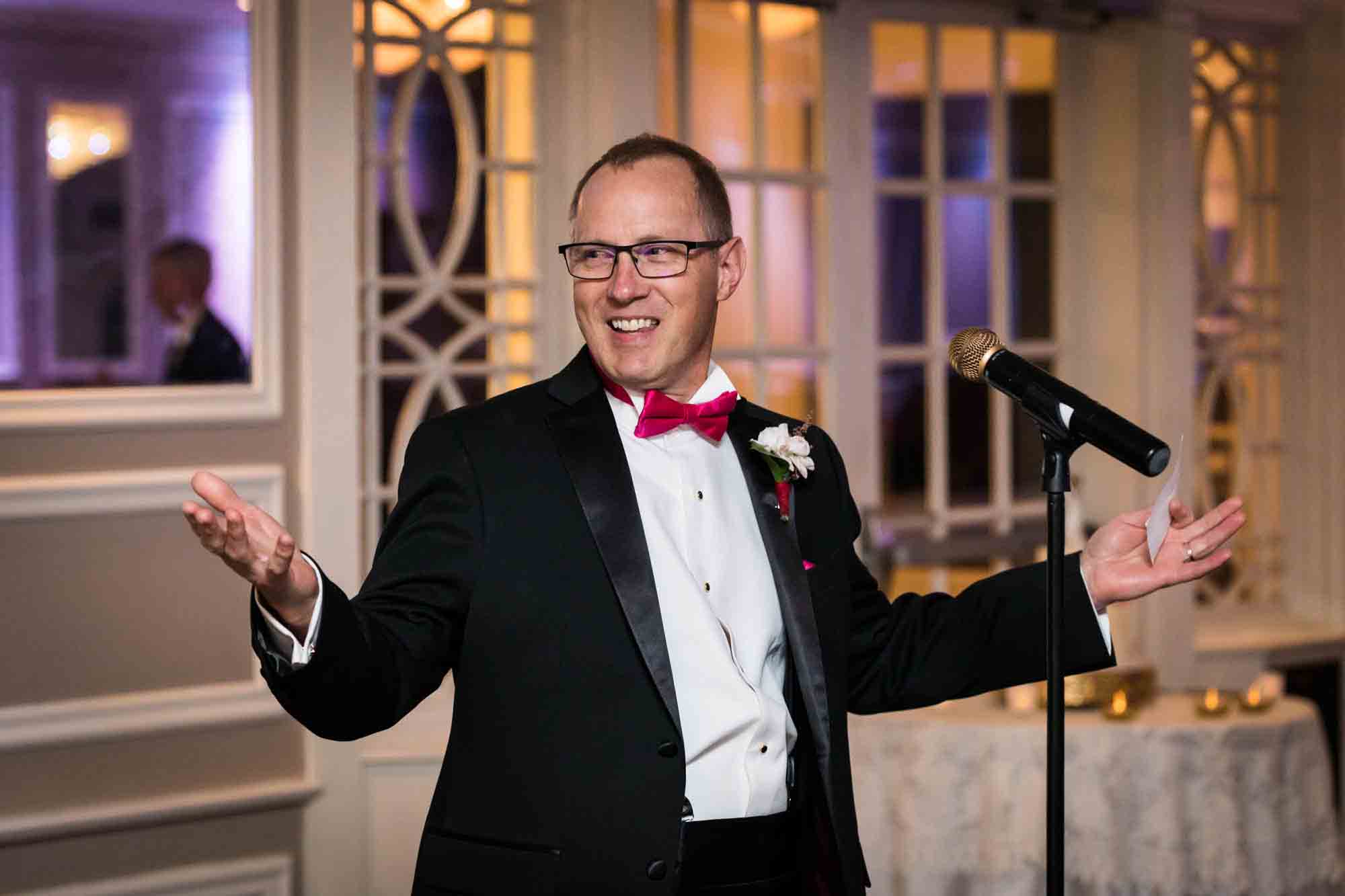 Father smiling with hands outstretched during speech at a Briarcliff Manor wedding
