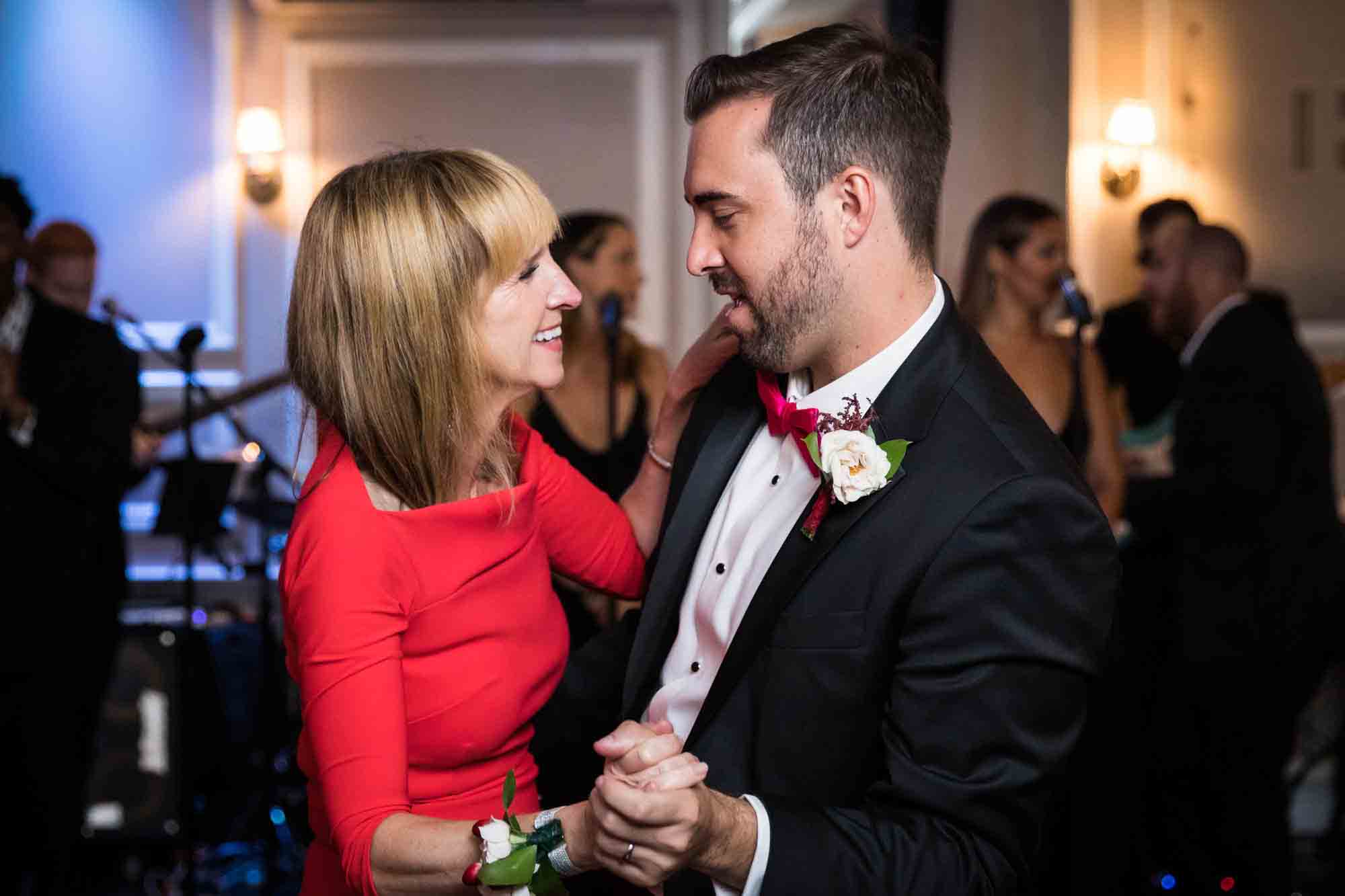 Groom dancing with mother wearing red long sleeved dress at a Briarcliff Manor wedding