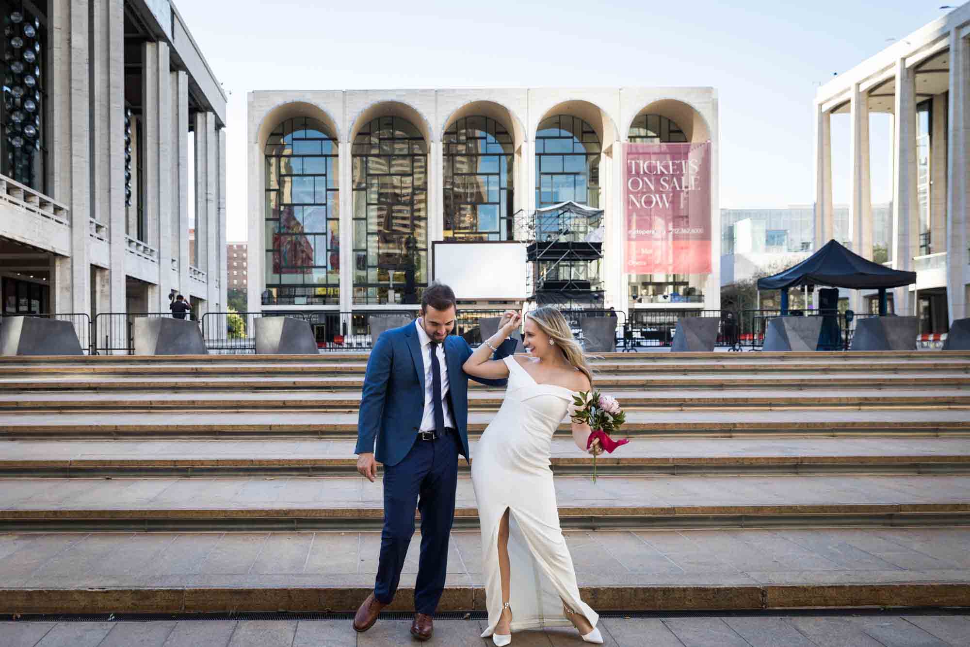 Bride and groom dancing in front of steps of Lincoln Plaza in NYC