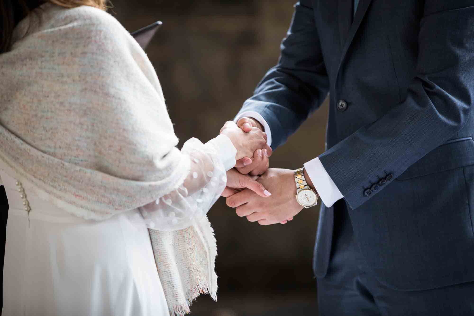 Bride and groom holding hands during a hand holding wedding ceremony