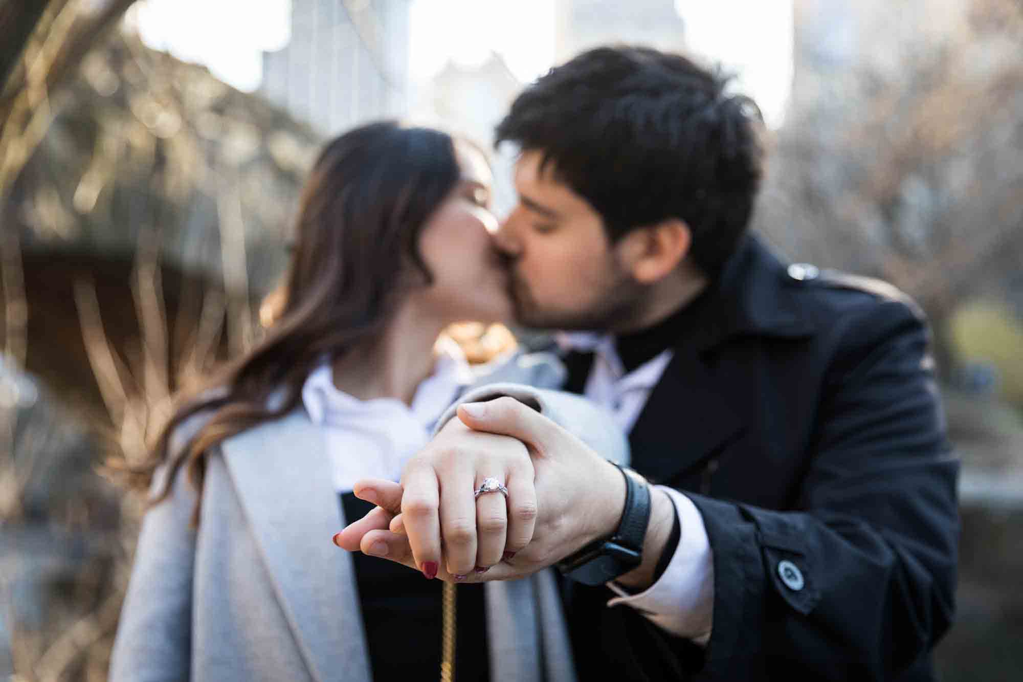 Couple kissing while hand outstretched showing engagement ring during a Central Park surprise proposal