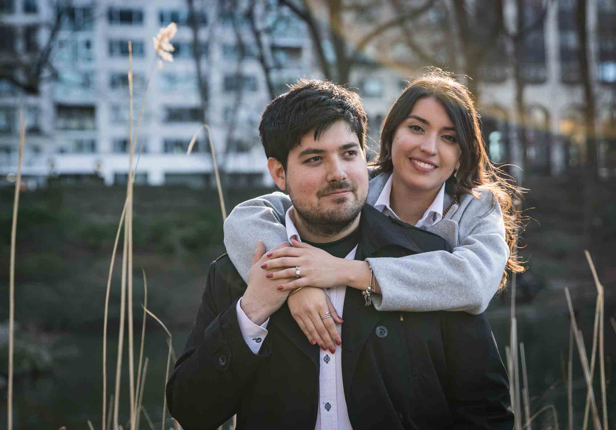 Woman hugging man with arms around his neck during a Central Park surprise proposal