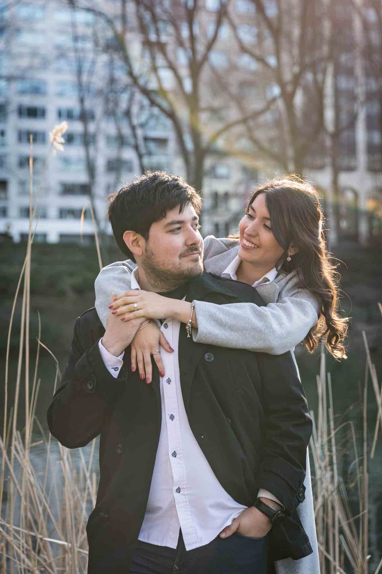 Couple looking at each other while woman hugs man around the neck during a Central Park surprise proposal