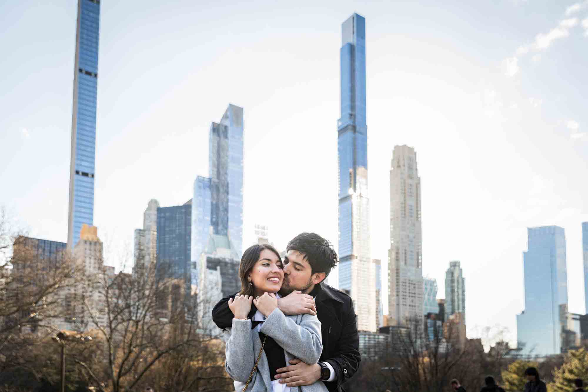 Couple hugging with NYC skyline in background during a Central Park surprise proposal