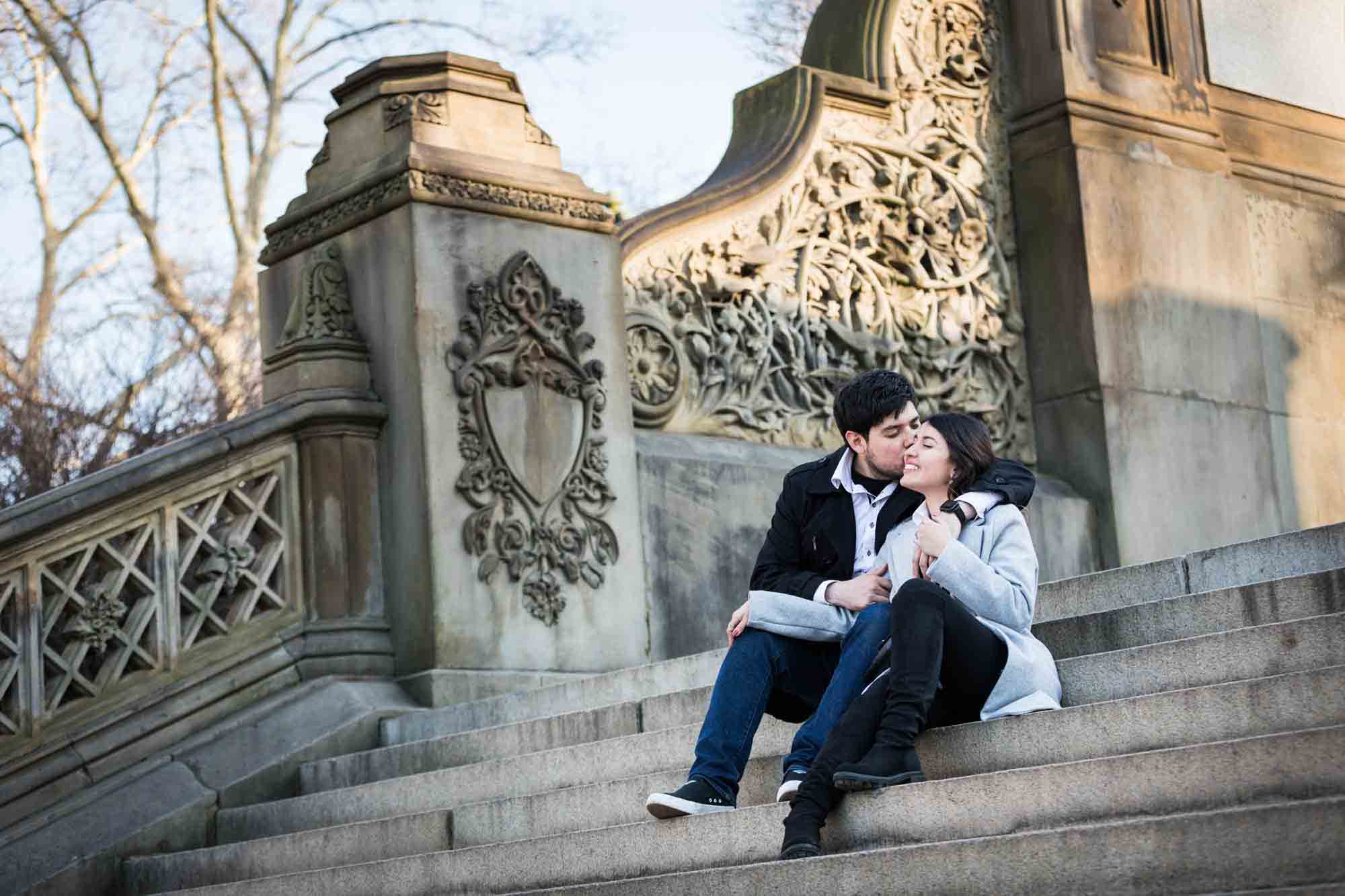 Couple kissing while sitting on Bethesda Terrace staircase after a NYC surprise proposal