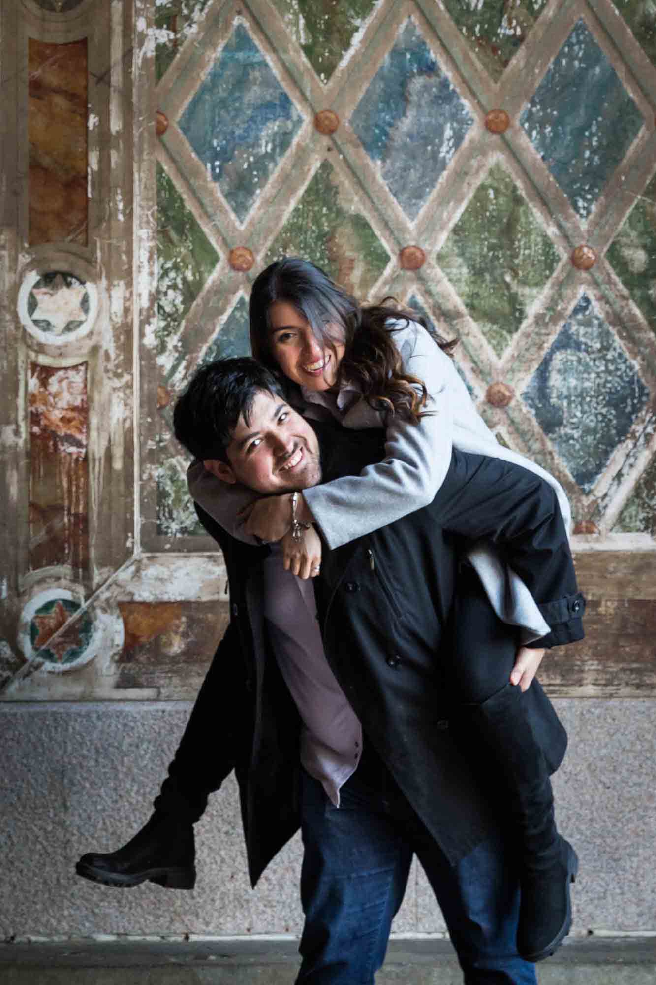 Man giving woman piggyback ride under Bethesda Terrace after a NYC surprise proposal