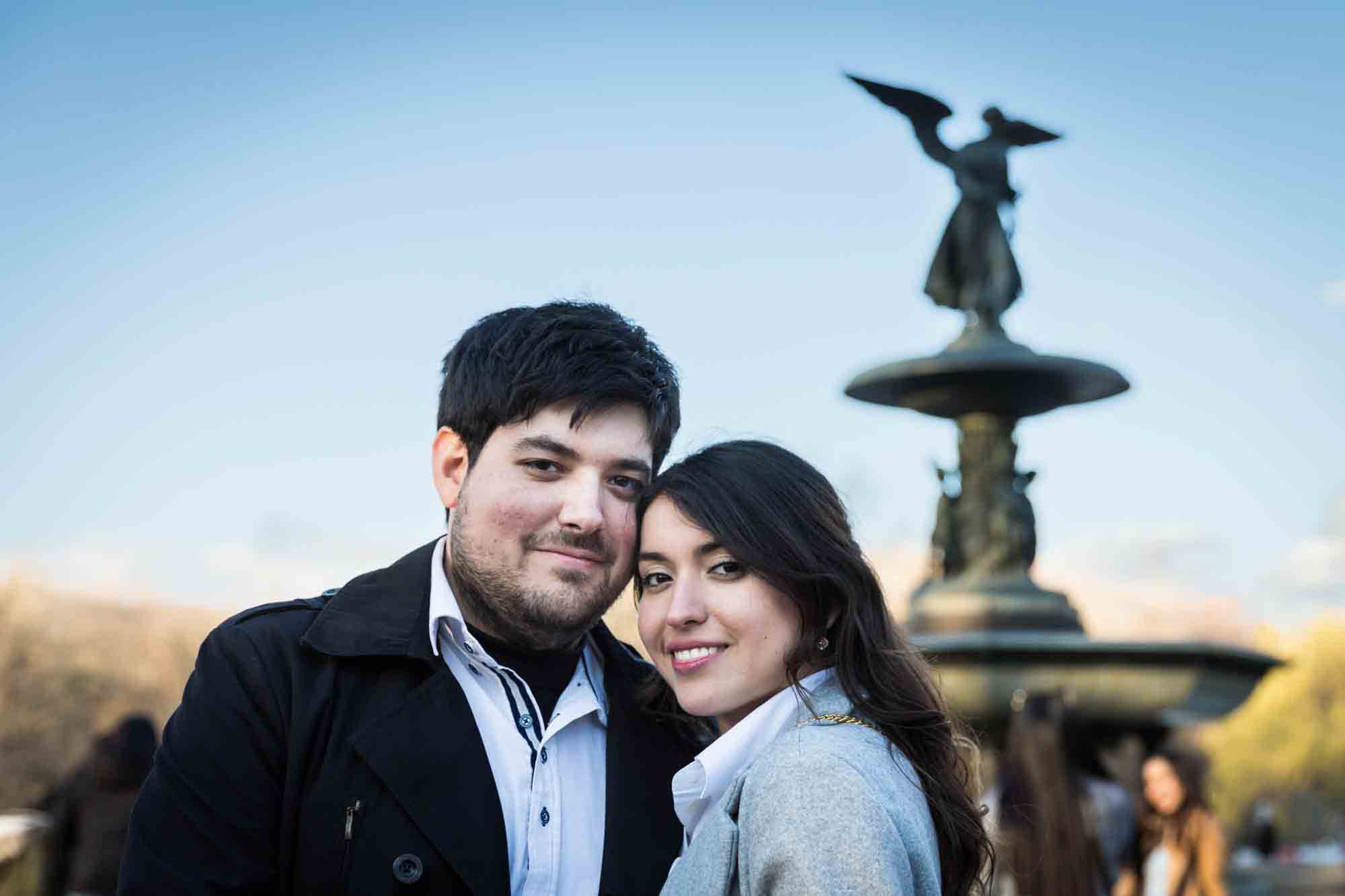 Couple with heads together in front of Bethesda Fountain after a NYC surprise proposal