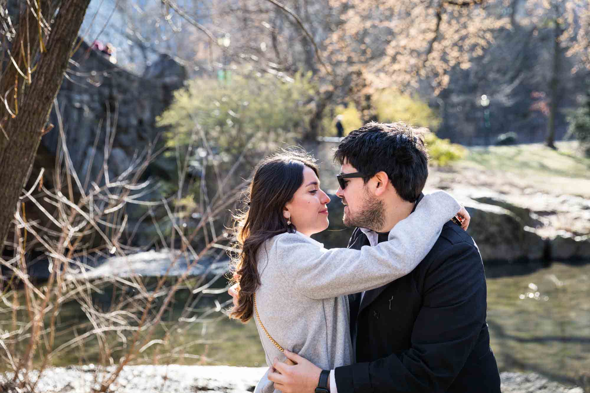 Man wearing sunglasses hugging woman during a Gapstow Bridge surprise proposal in Central Park