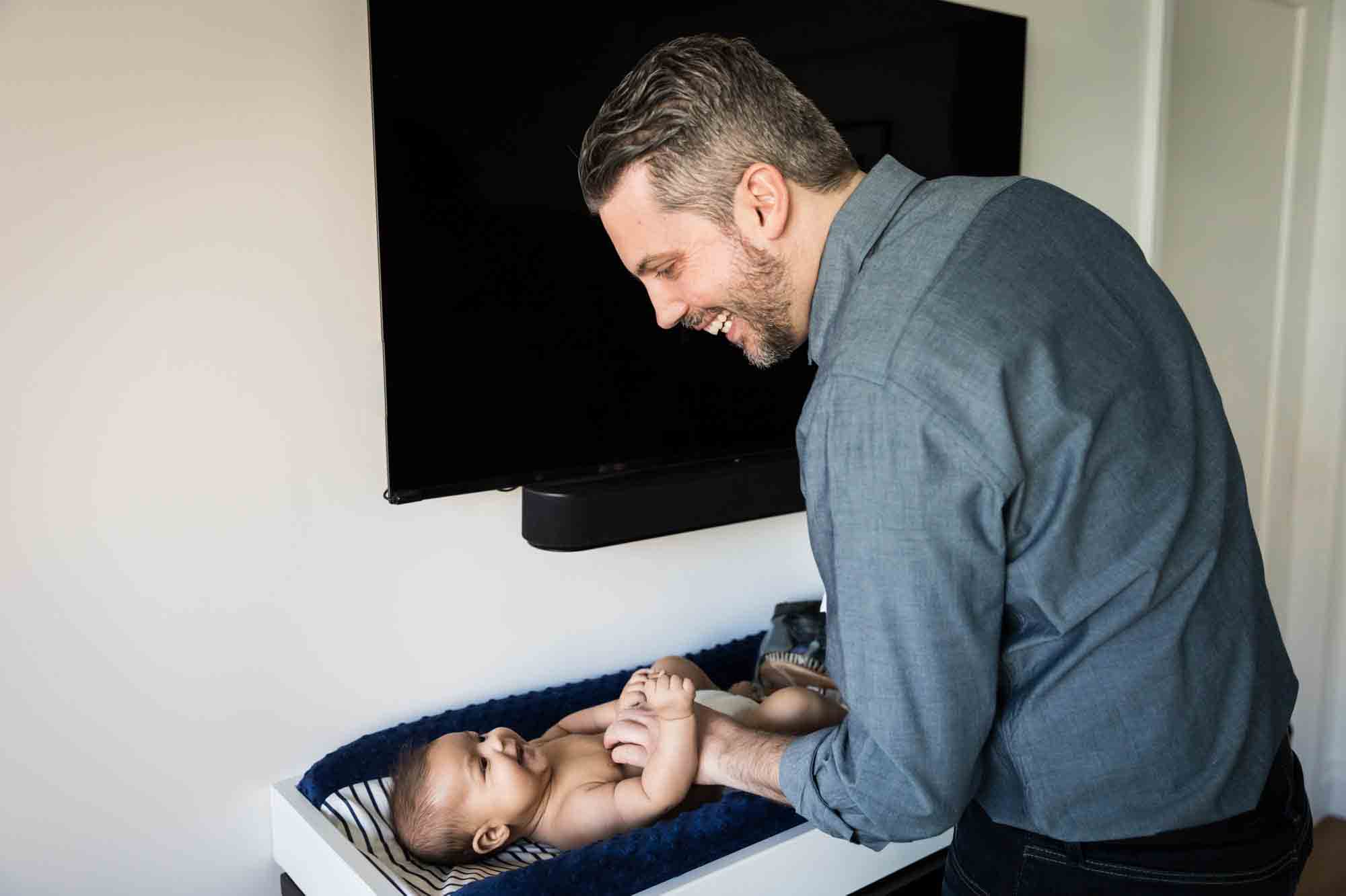 Father playing with baby on changing table during a Manhattan family portrait session