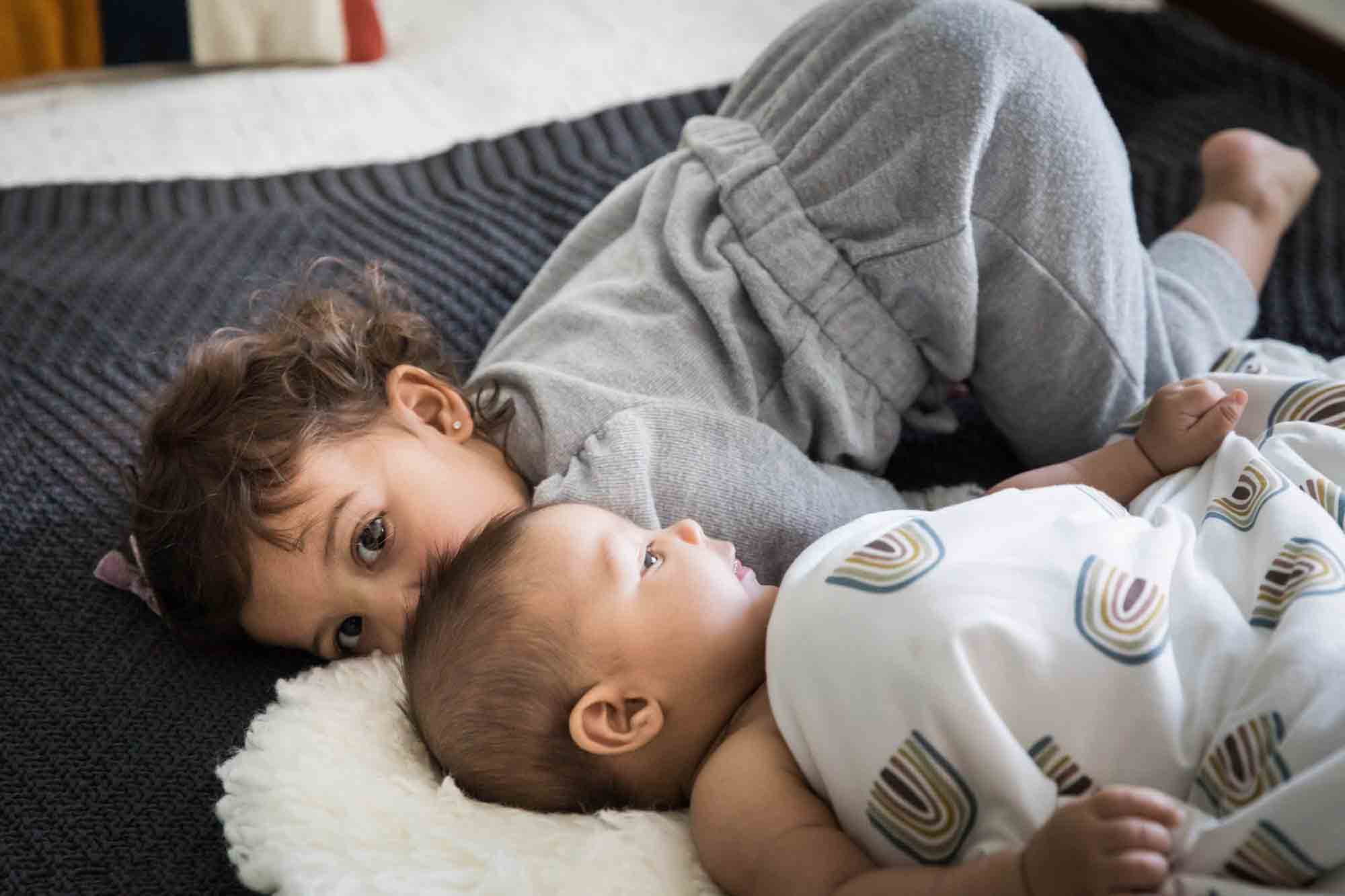 Toddler playing with baby on bed during a Manhattan family portrait session