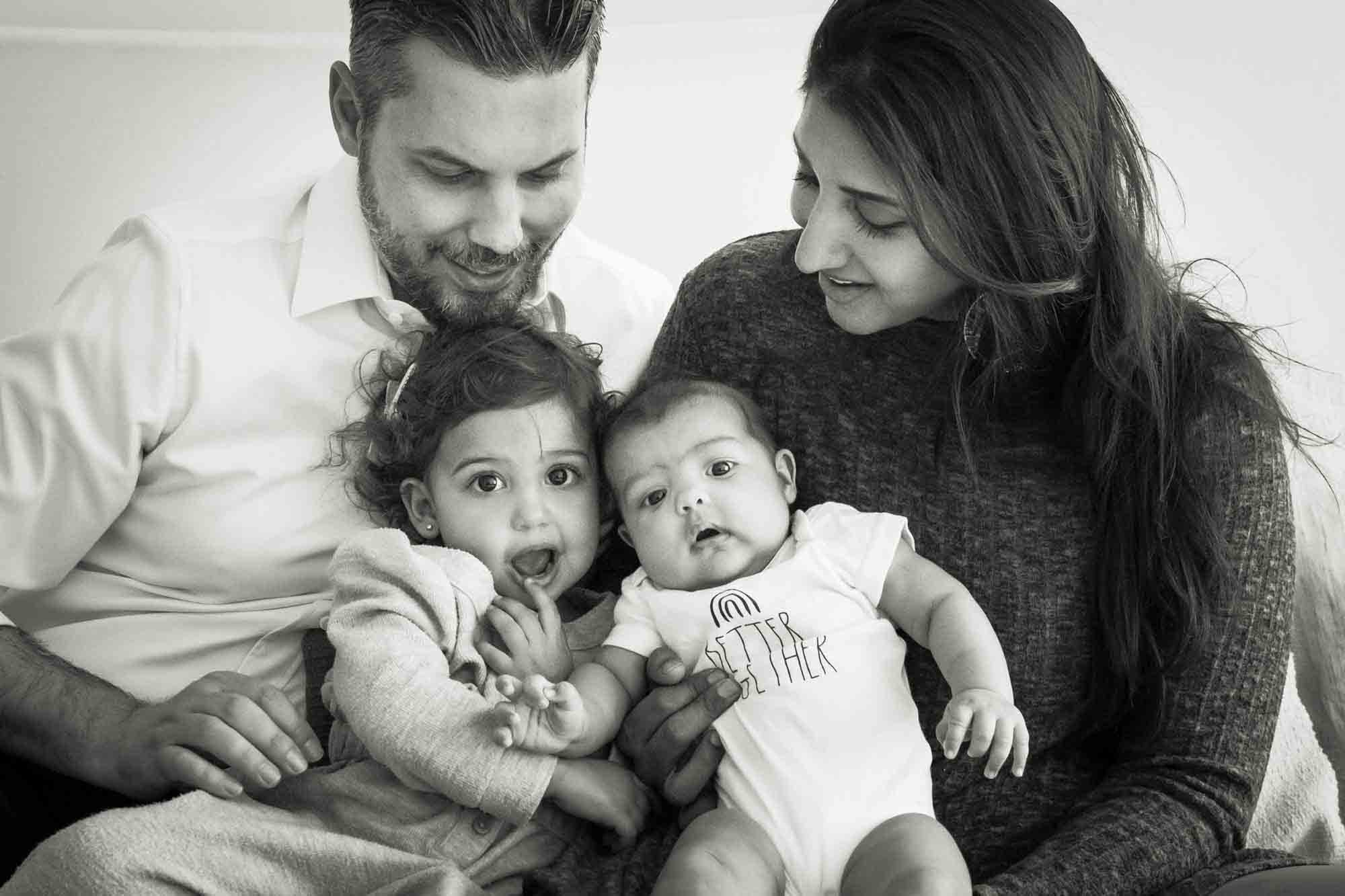 Manhattan family portrait session of parents holding toddler and baby on bed