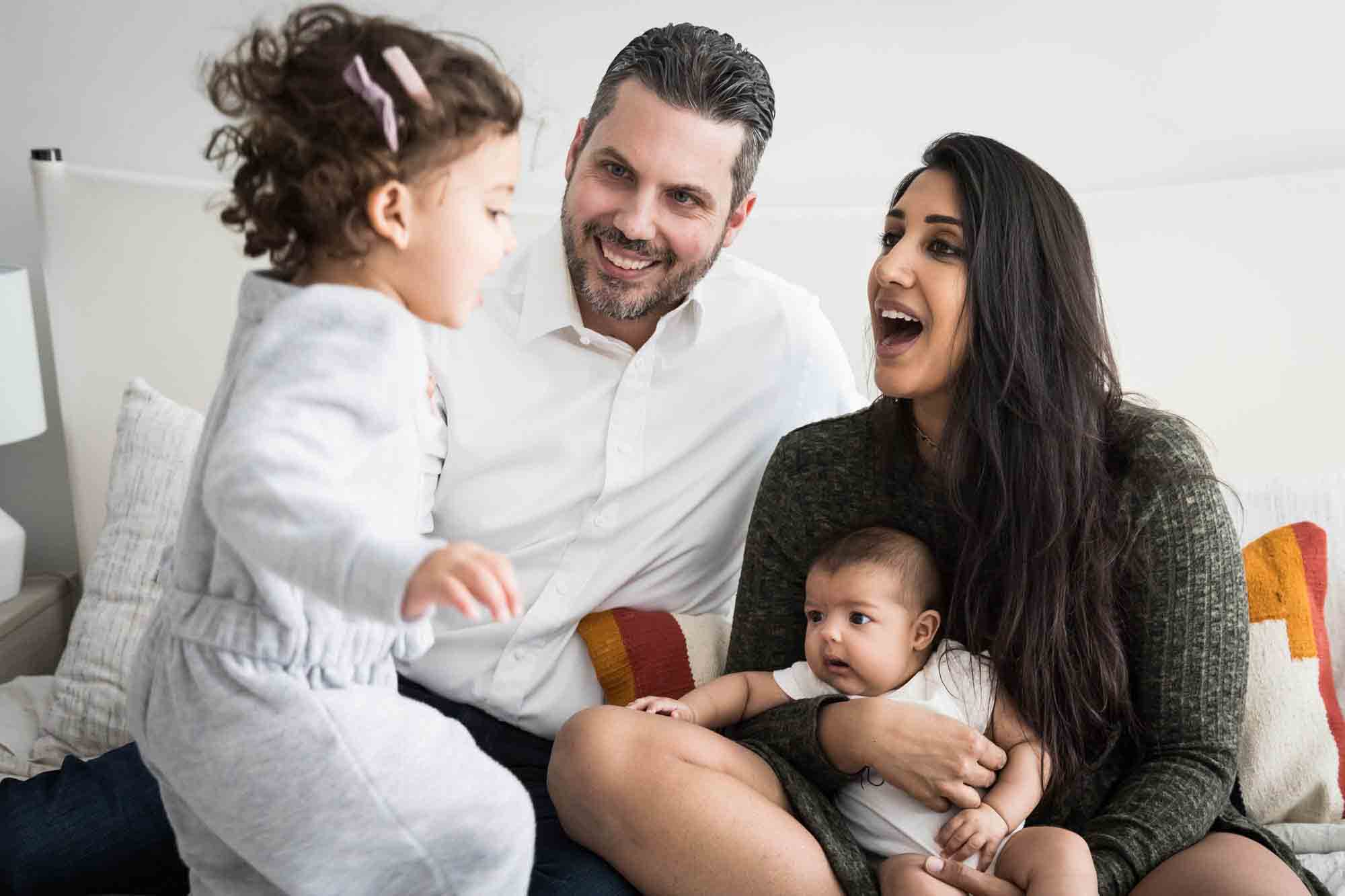 Manhattan family portrait session of parents playing with toddler and baby on bed