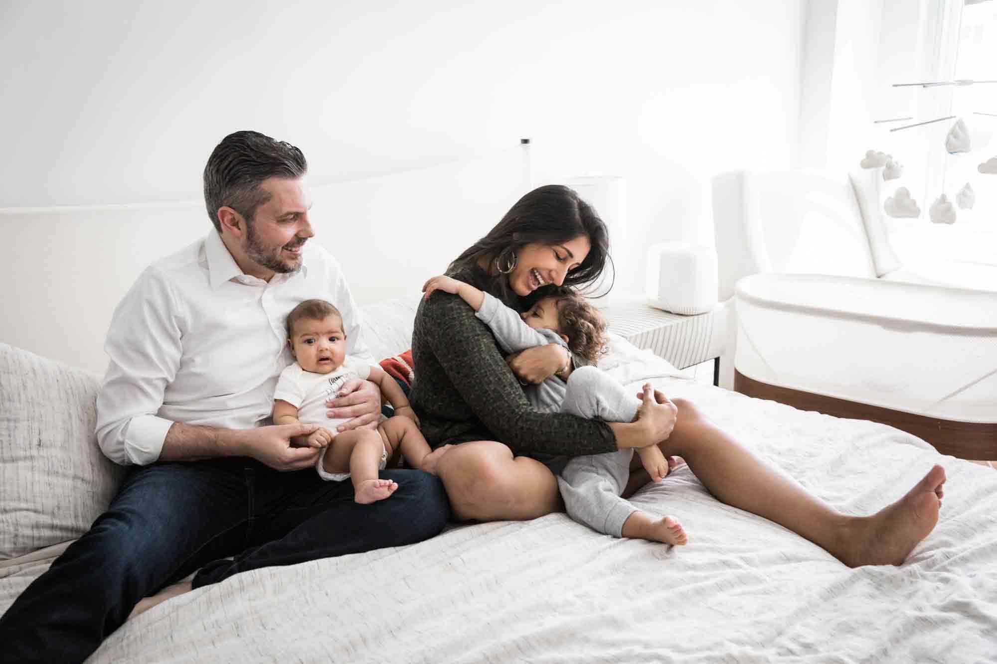 Manhattan family portrait session of parents playing with toddler and baby on bed