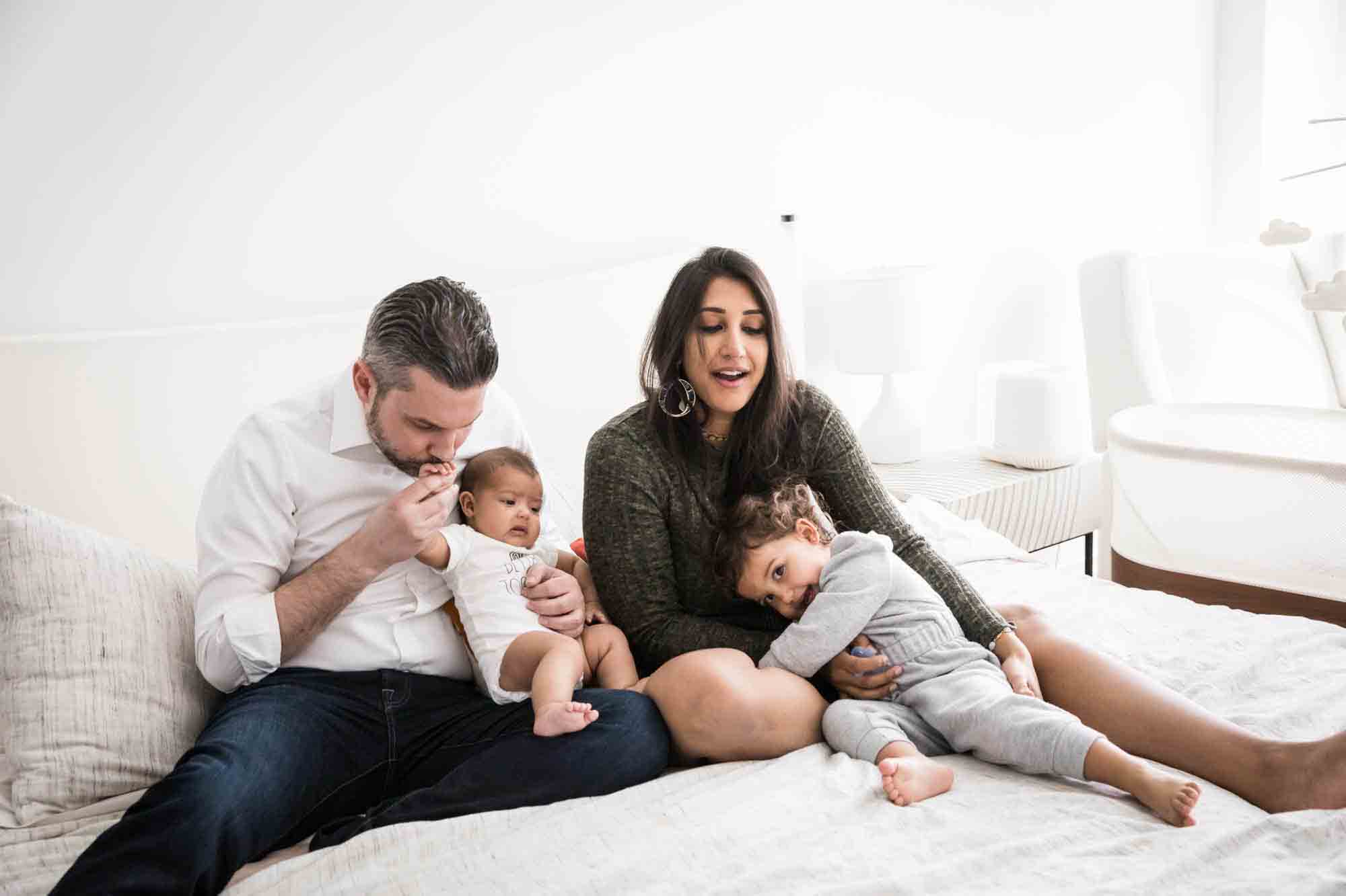 Manhattan family portrait session of parents holding toddler and baby on bed