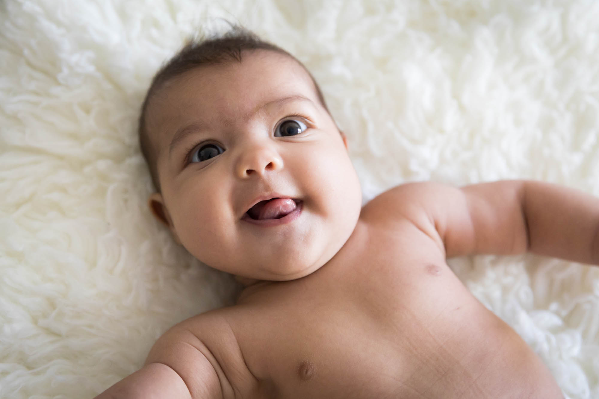 Manhattan family portrait session of smiling baby laying on white rug