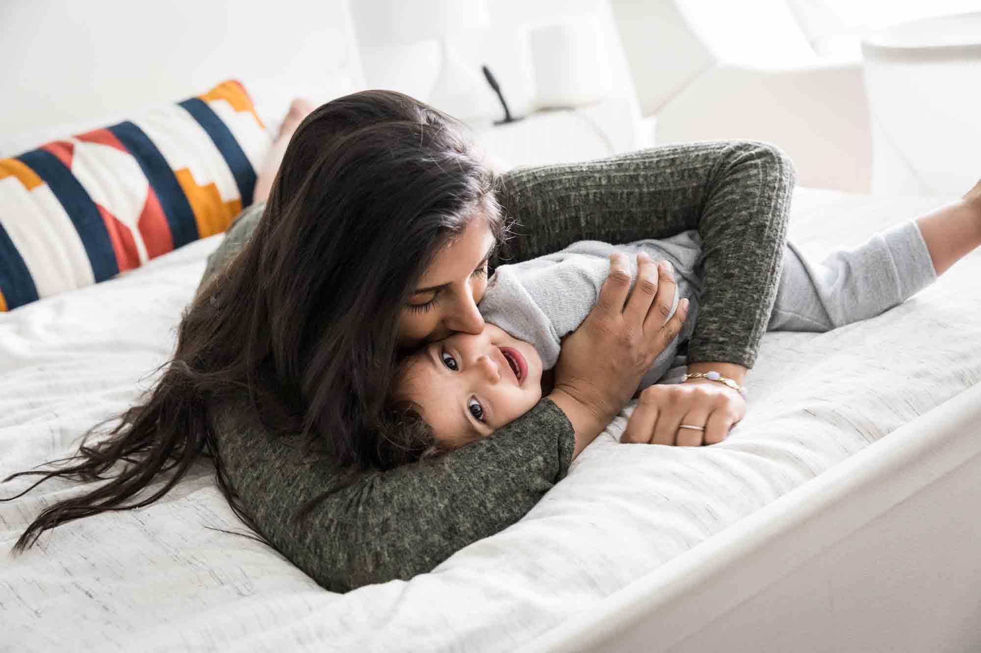 Mother kissing toddler on the bed during a NYC family portrait session