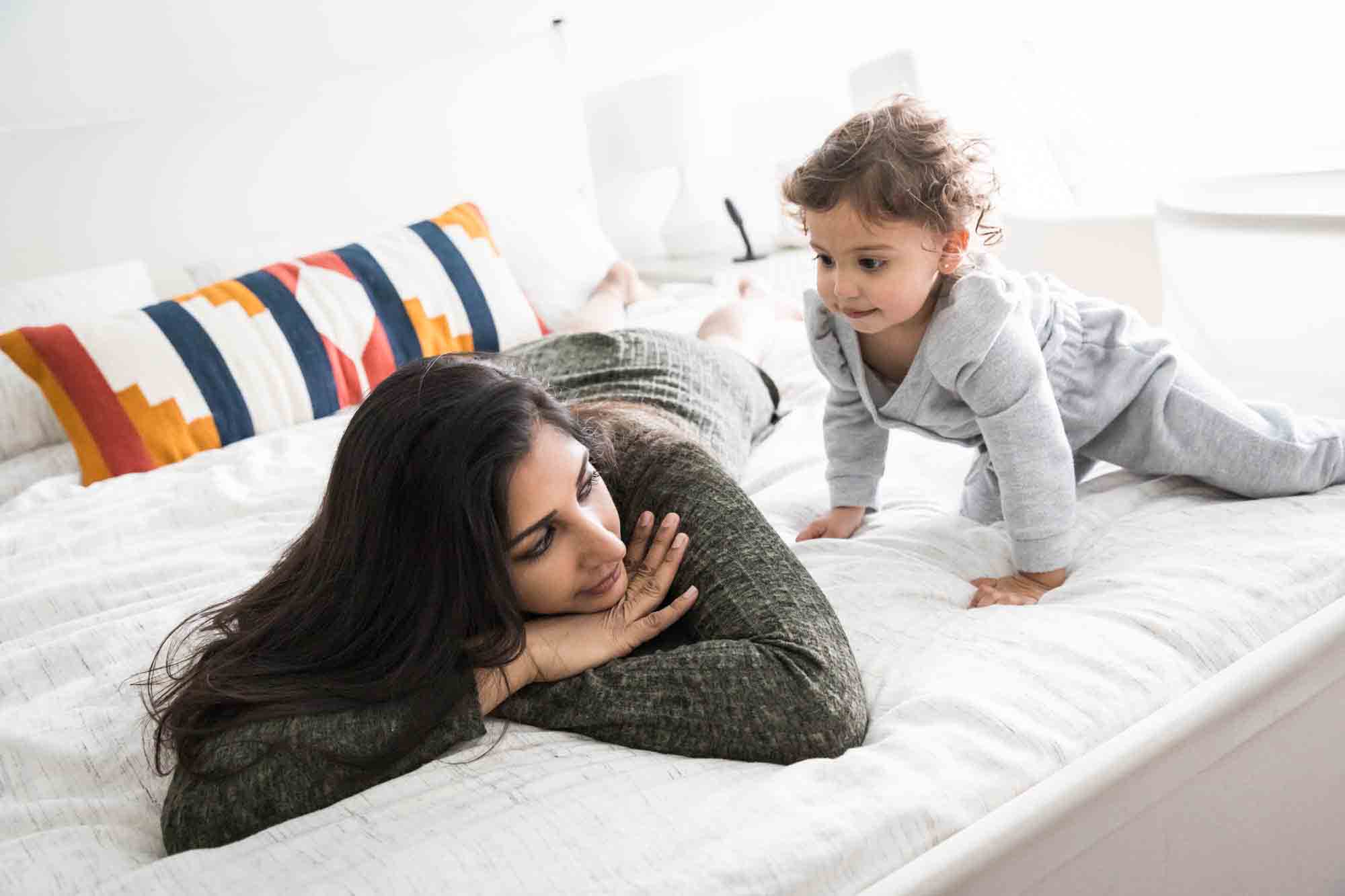 Mother and toddler playing on the bed during a NYC family portrait session