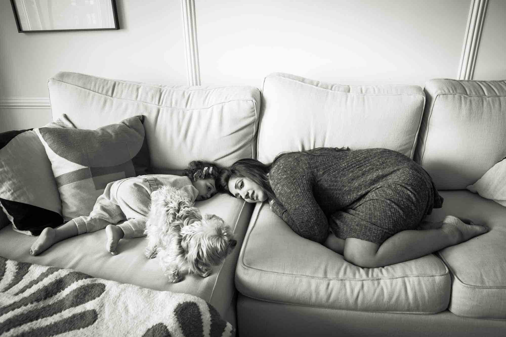 Mother and toddler lying on couch playing with dog during a NYC family portrait session