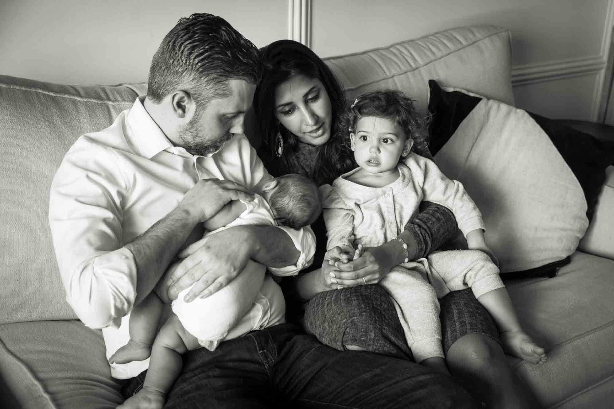 Black and white photo of Manhattan family portrait session of parents and two little children sitting on couch