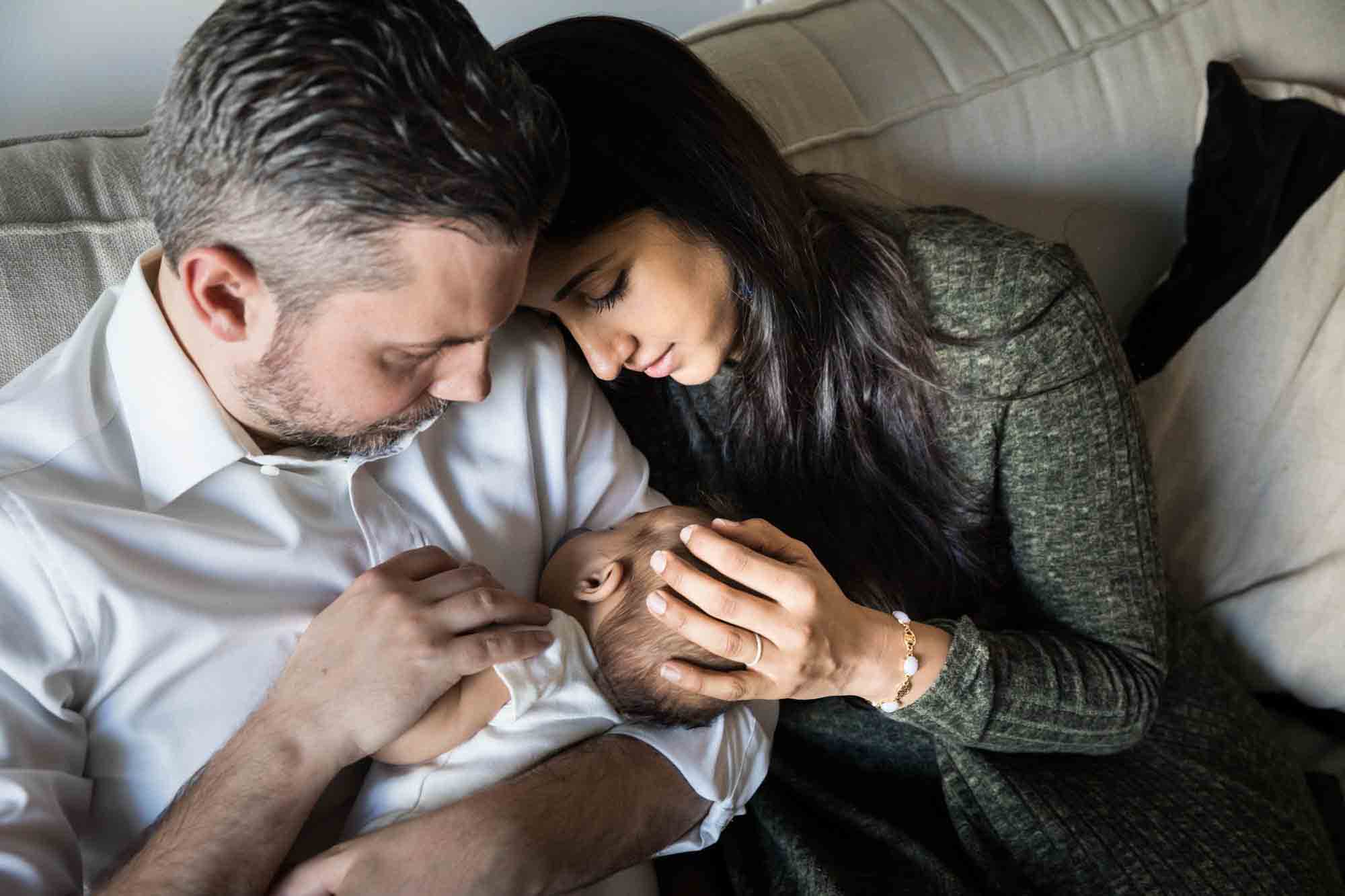 Parents looking at newborn while sitting on couch