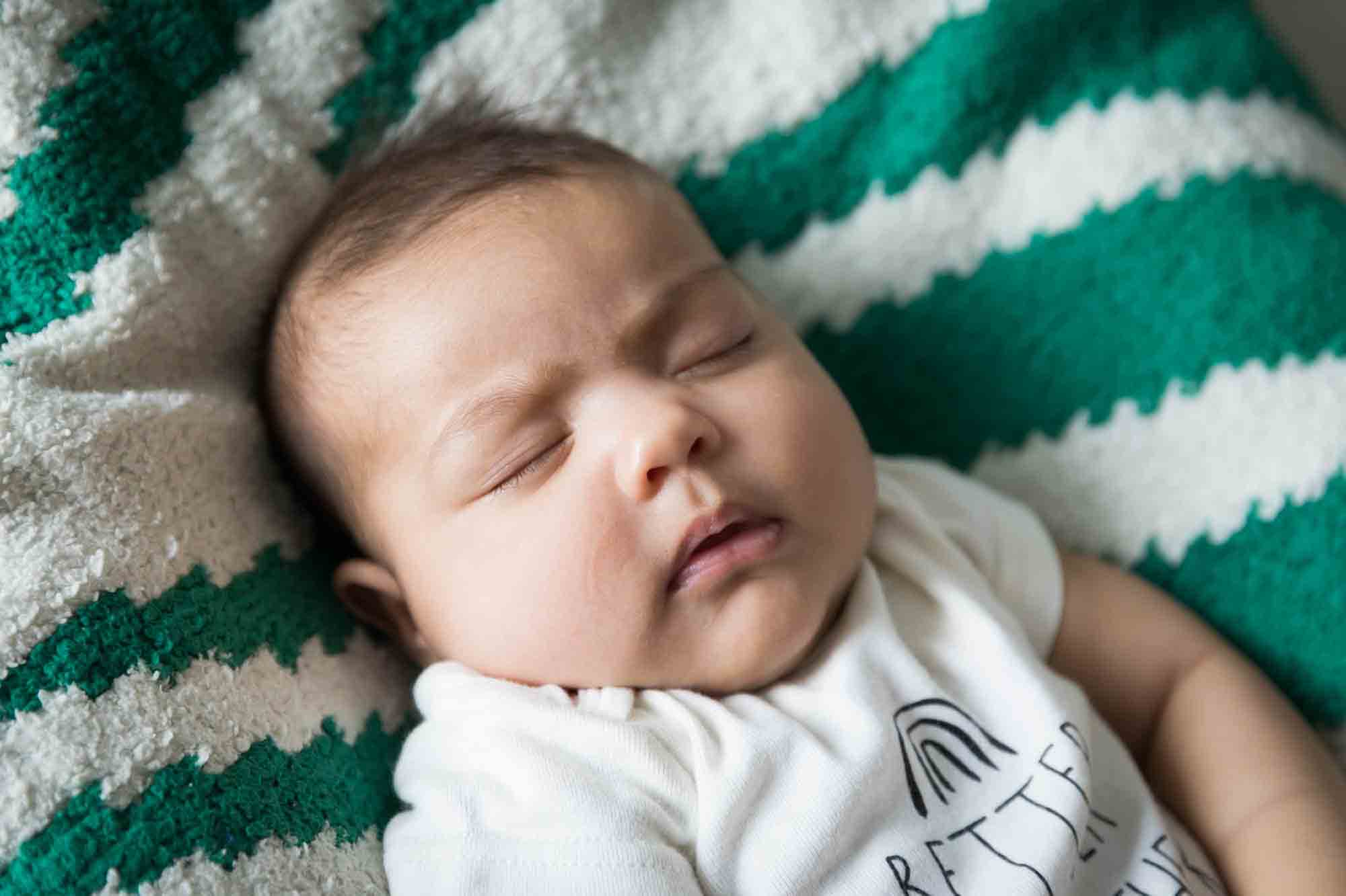 Sleeping newborn baby on green and white blanket during a New York family portrait session