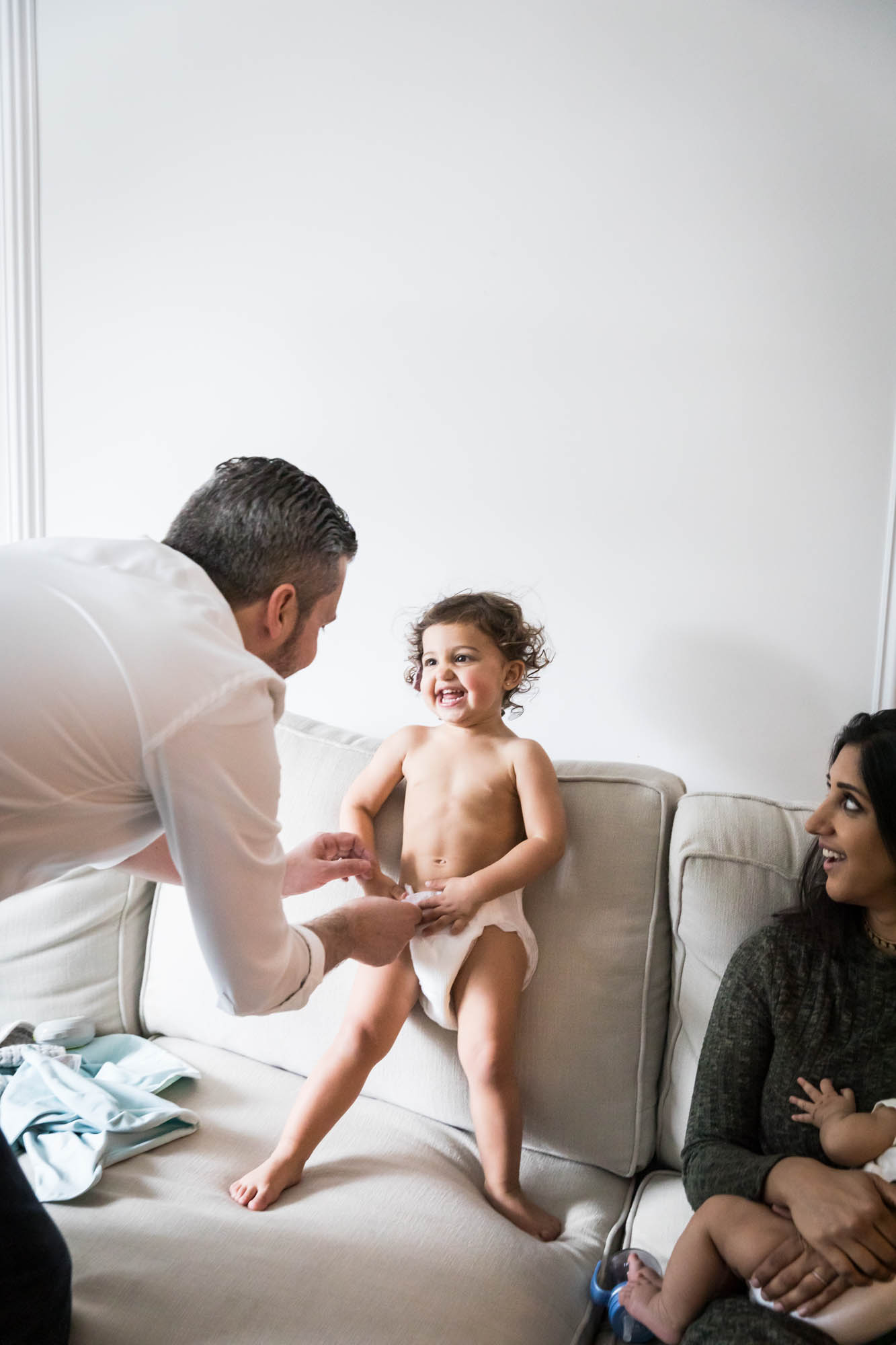 Parents playing with toddler on couch during a New York family portrait session