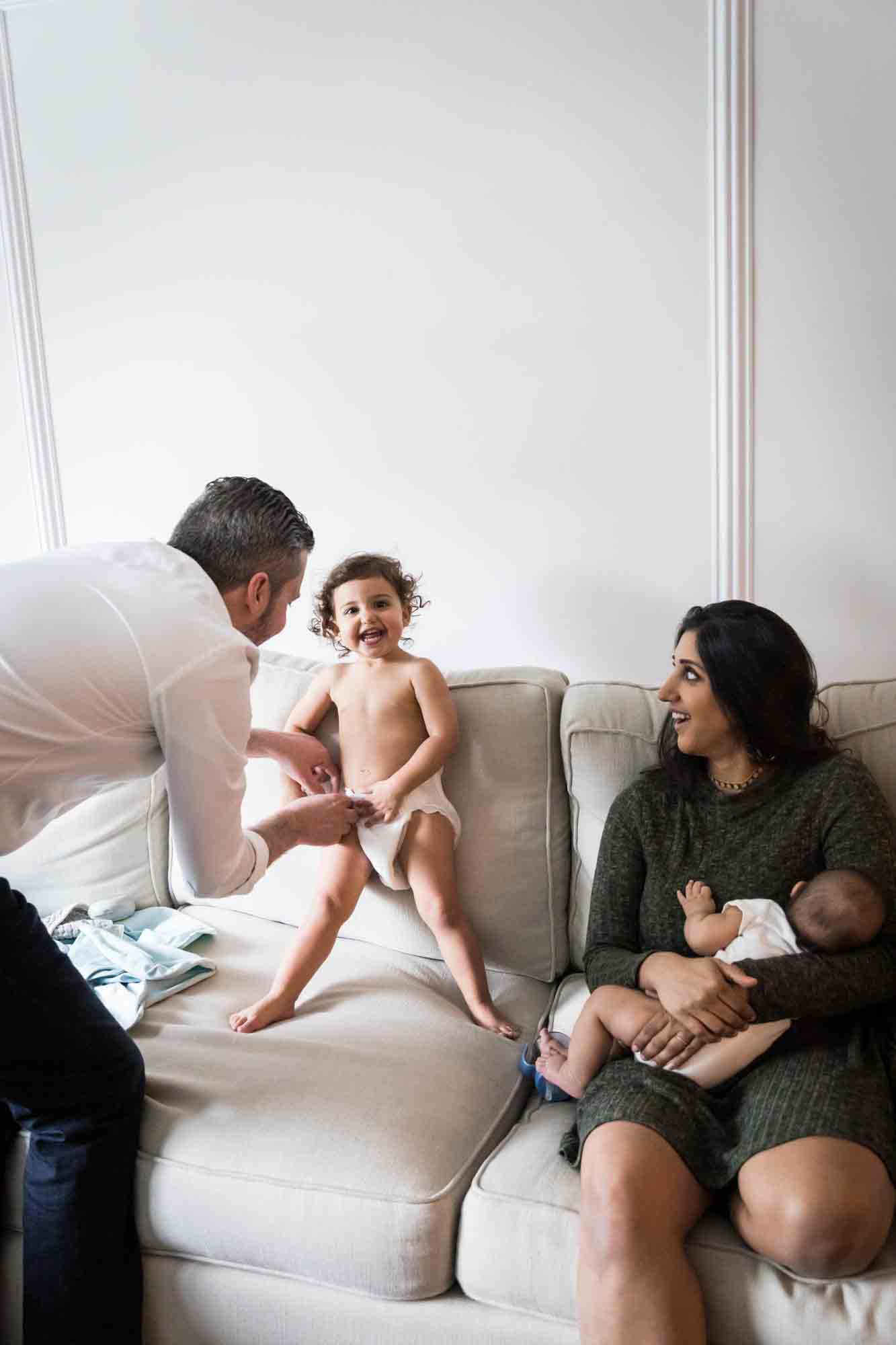 Parents playing with toddler on couch during a New York family portrait session