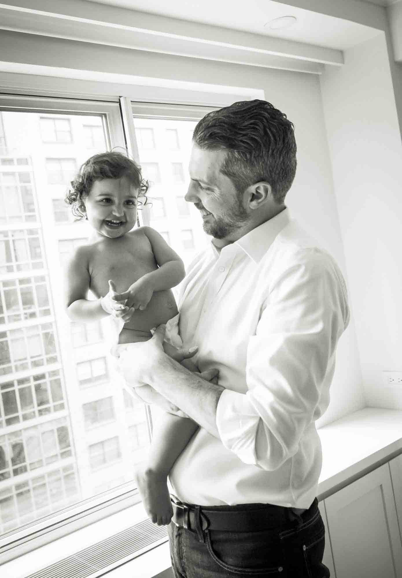 Manhattan family portrait session of father holding toddler in front of window