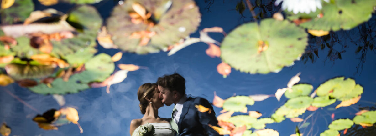 Conservatory Garden wedding photos of bride and groom kissing reflected in pond
