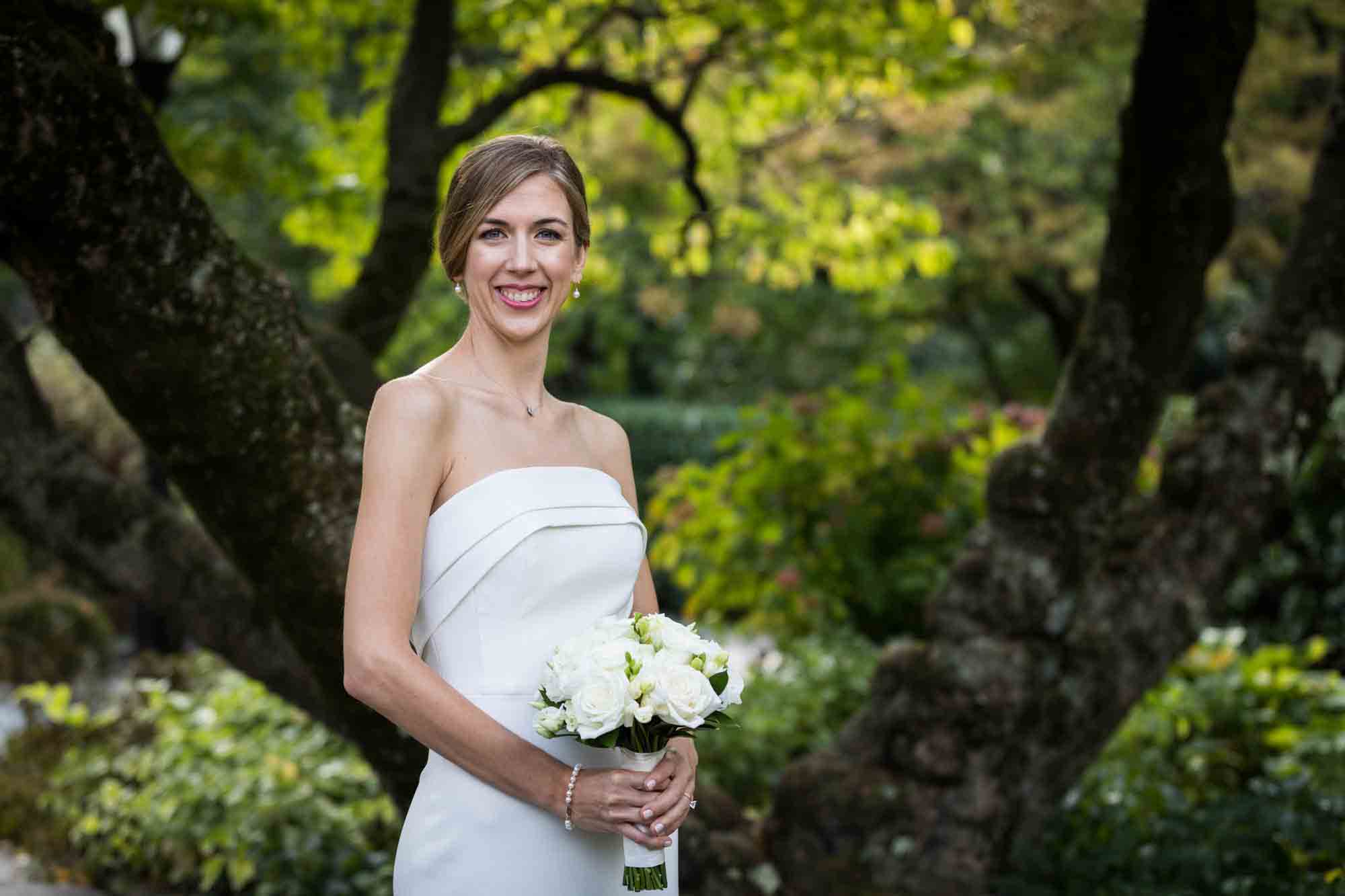 Conservatory Garden wedding photos of bride wearing strapless gown holding flower bouquet