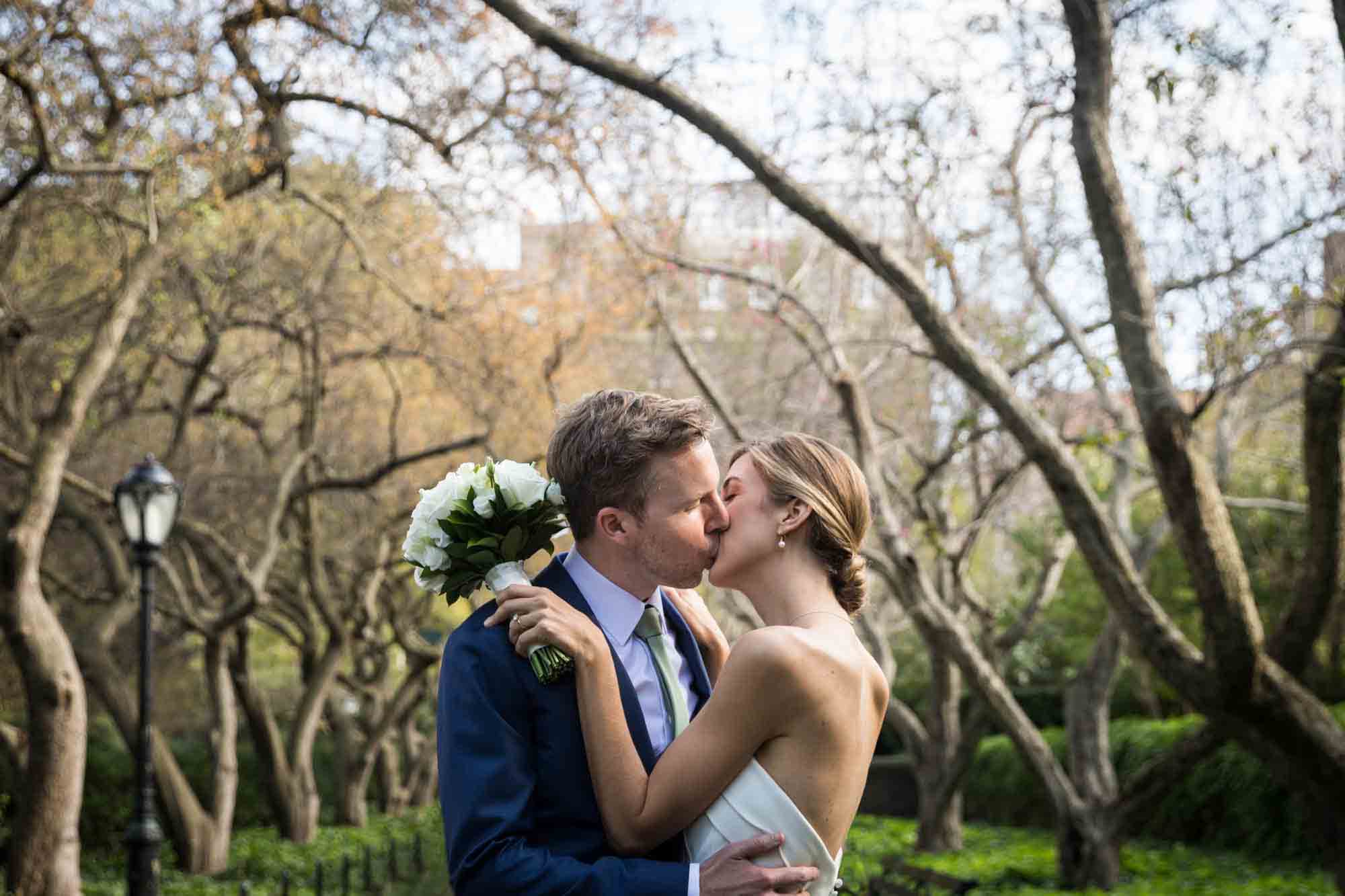 Conservatory Garden wedding photos of bride and groom kissing under tree branches